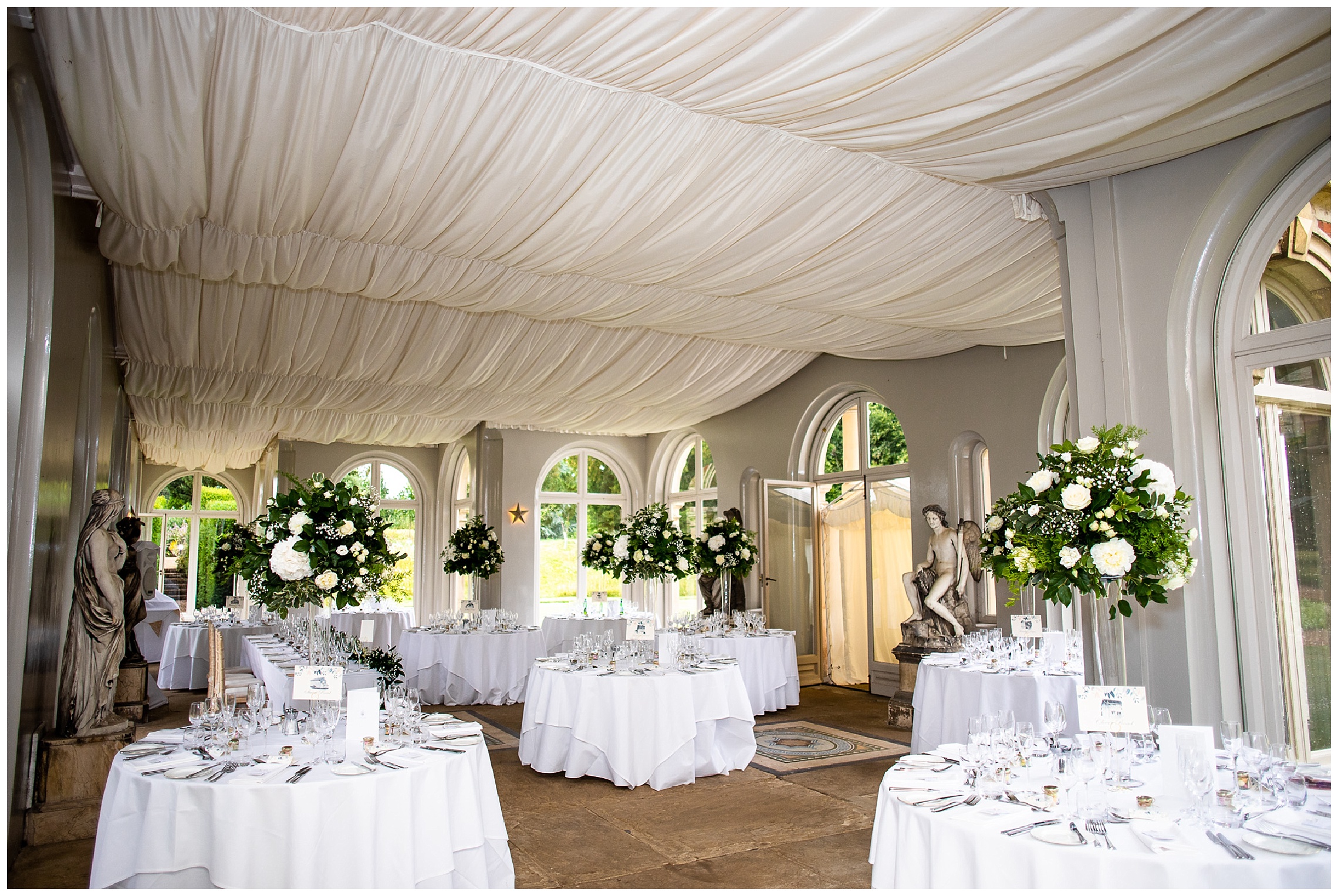 marquee style venue at somerleyton hall with white tablecloths and tall white floral centrepieces