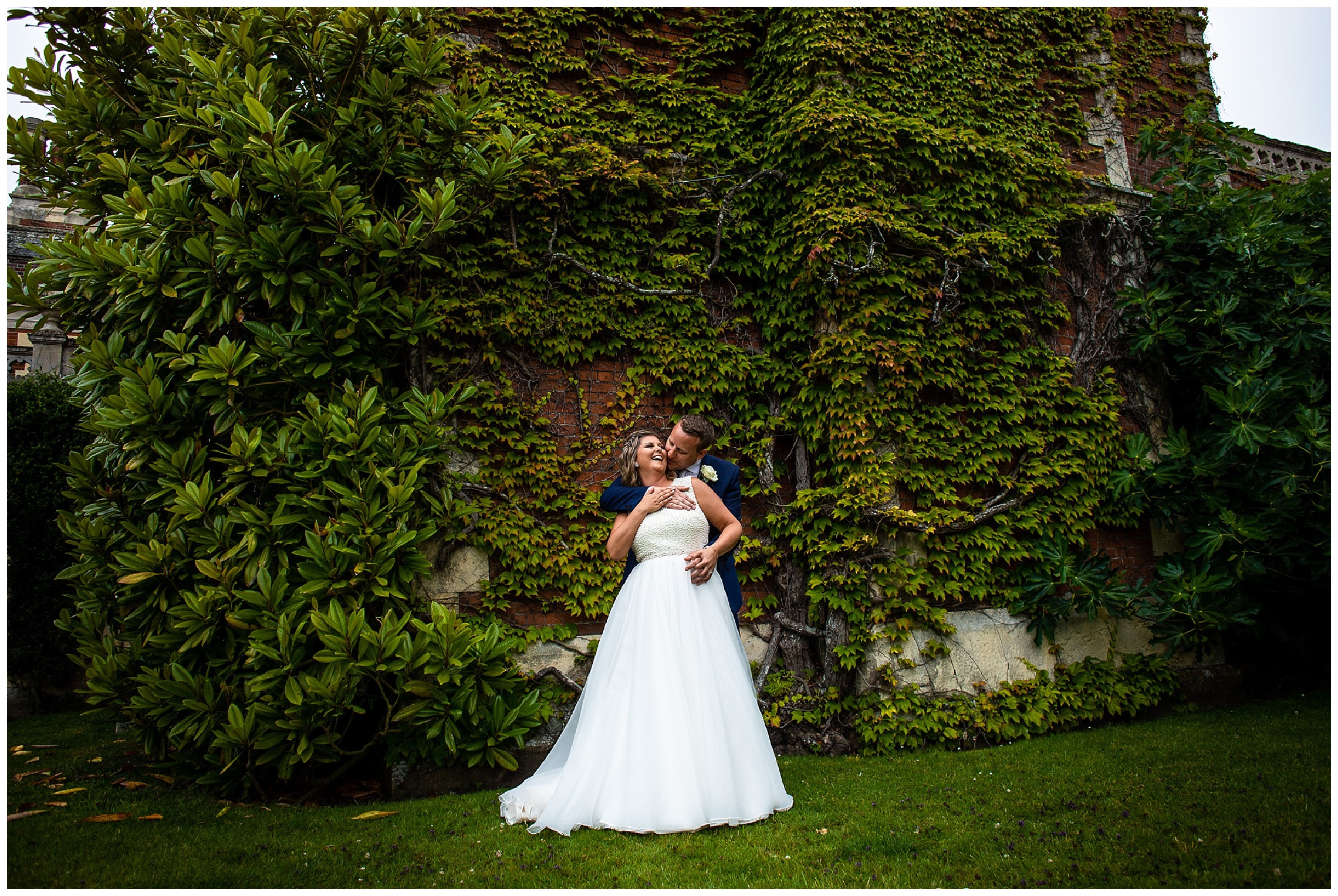 bride and groom laugh in front of ivy wall