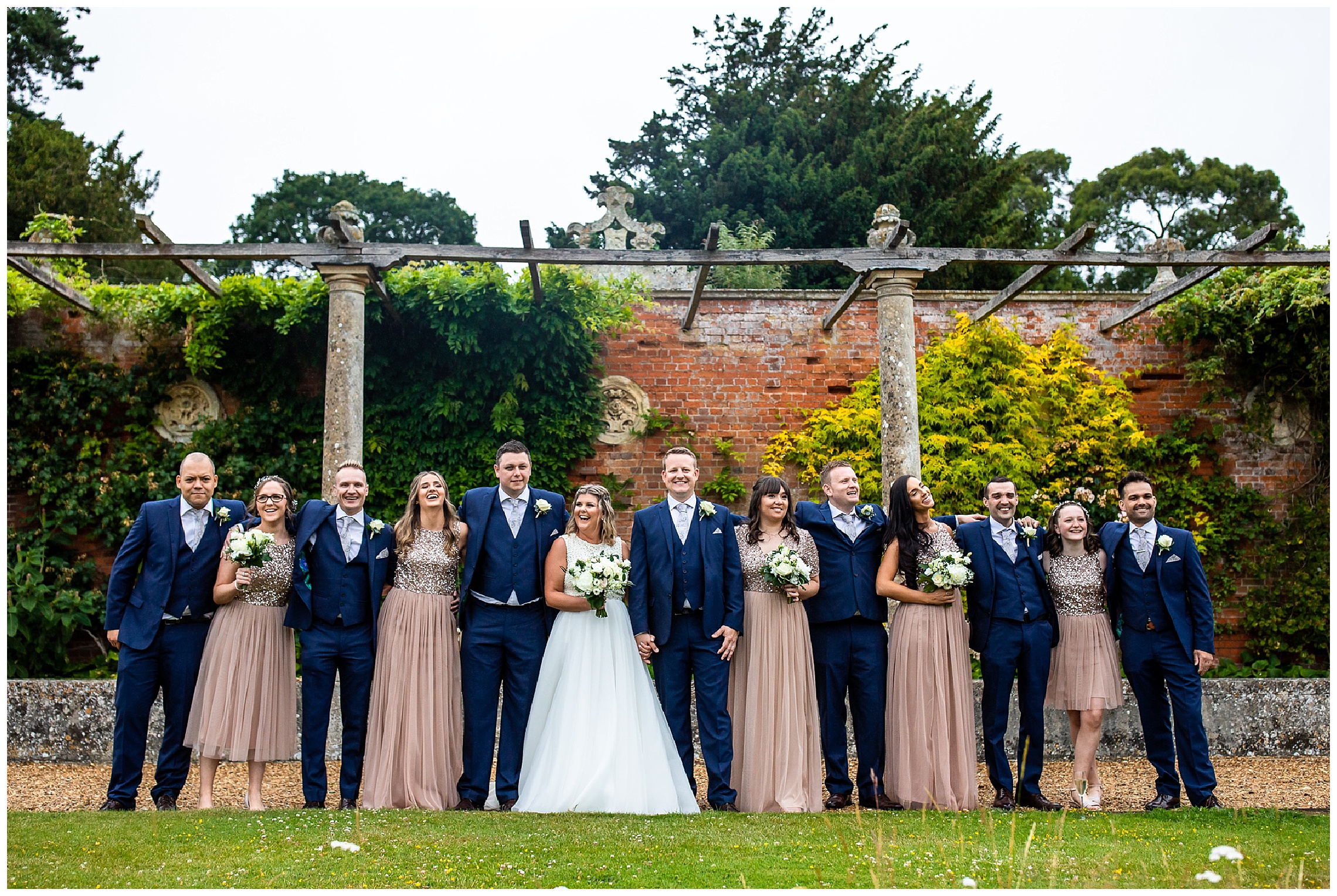 bridesmaids in pink dresses and groomsmen in blue suits at someleyton hall gardens