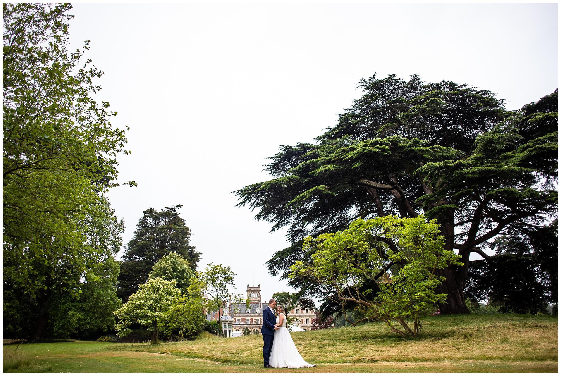 bride and groom stood together in front of somerleyton hall wide shot