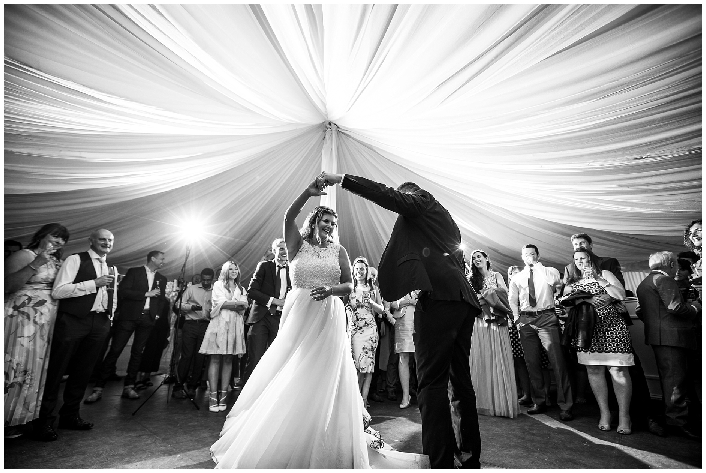 bride spins under grooms arm during first dance in marquee venue