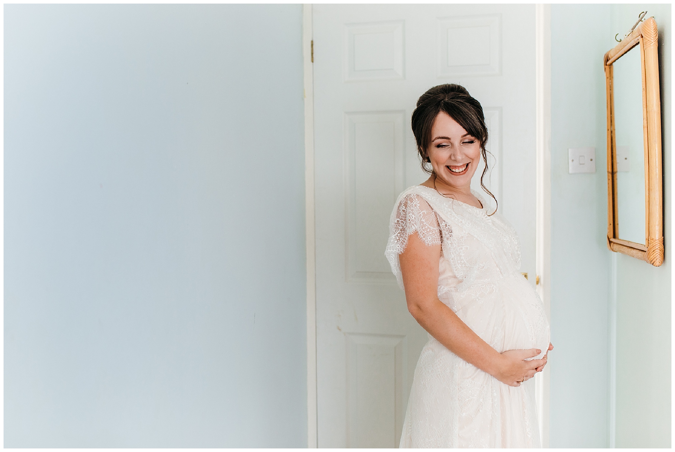 pregnant bride in belle and bunty wedding dress smiles, looks down and holds onto her bump