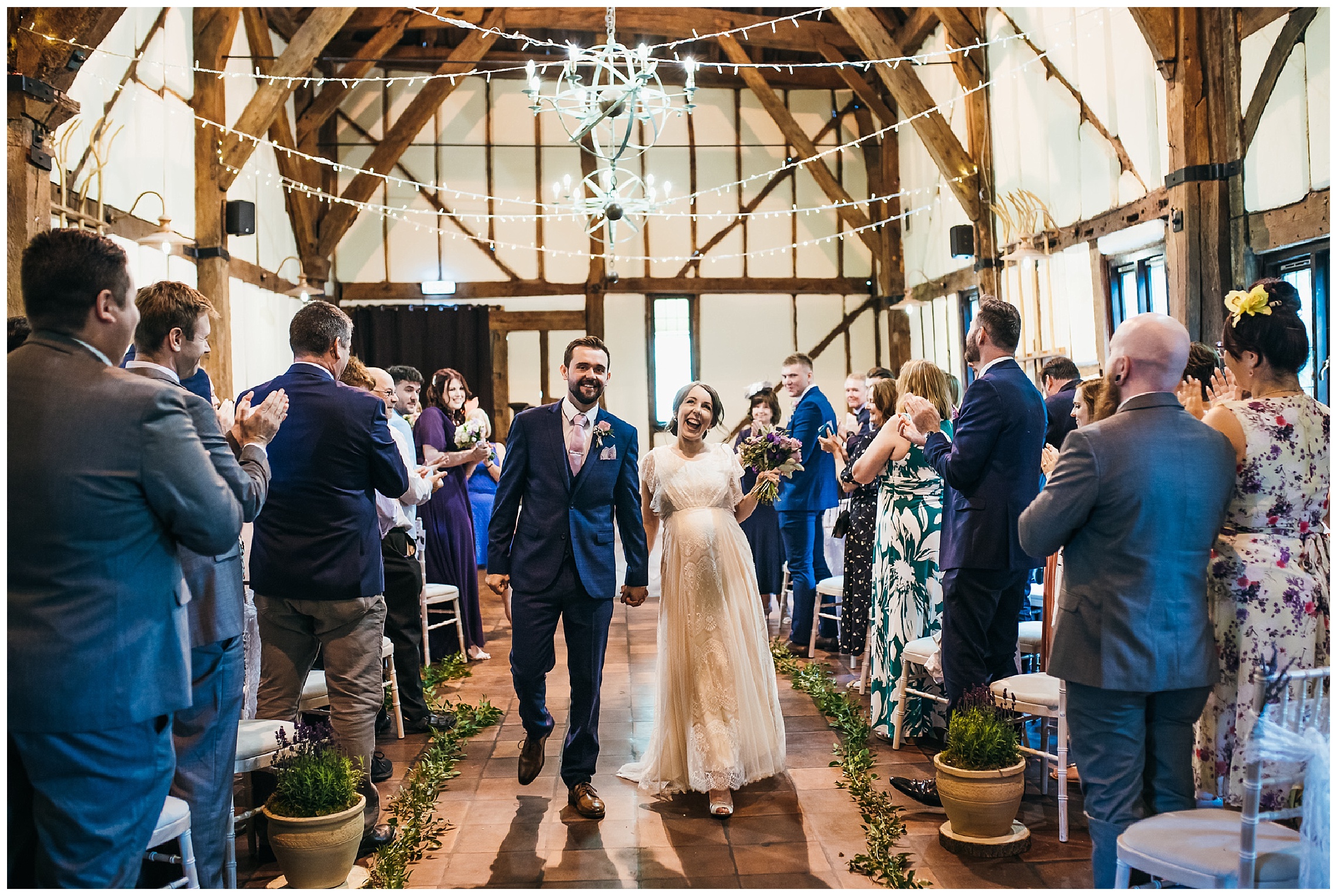 bride and groom walk out of barn wedding venue together smiling