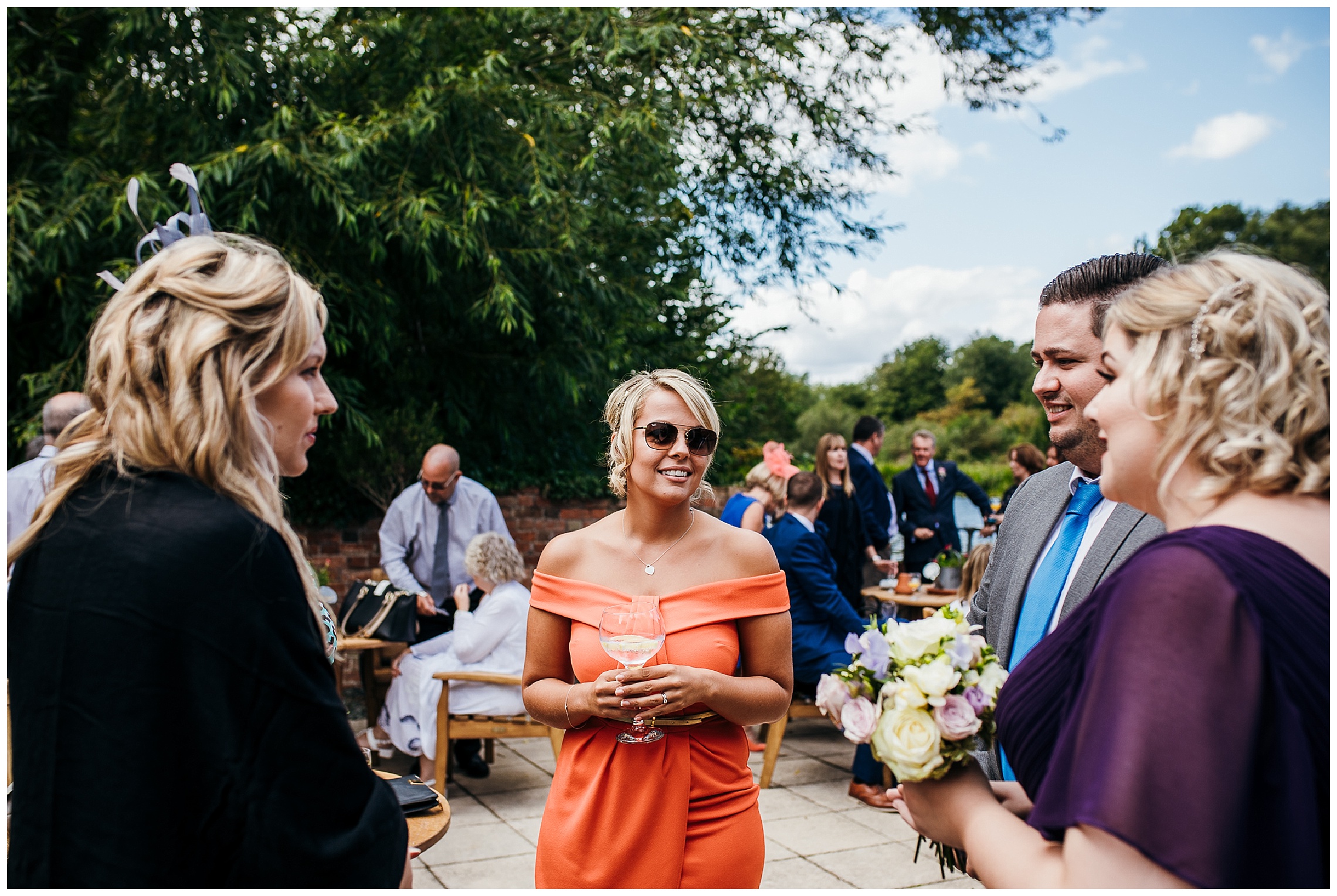 wedding guest in orange dress and sunglasses having fun