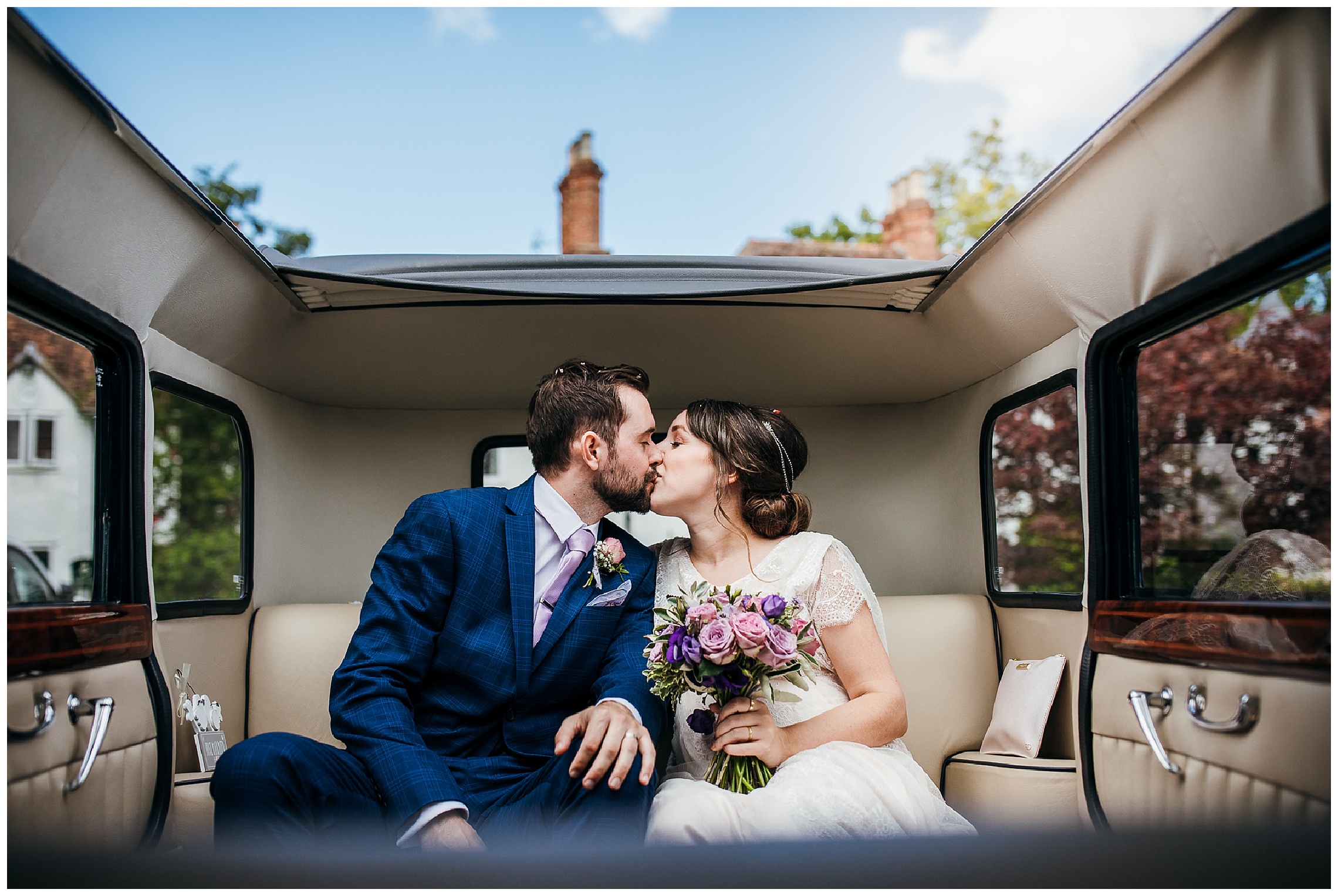 bride and groom in wedding car with roof down kissing