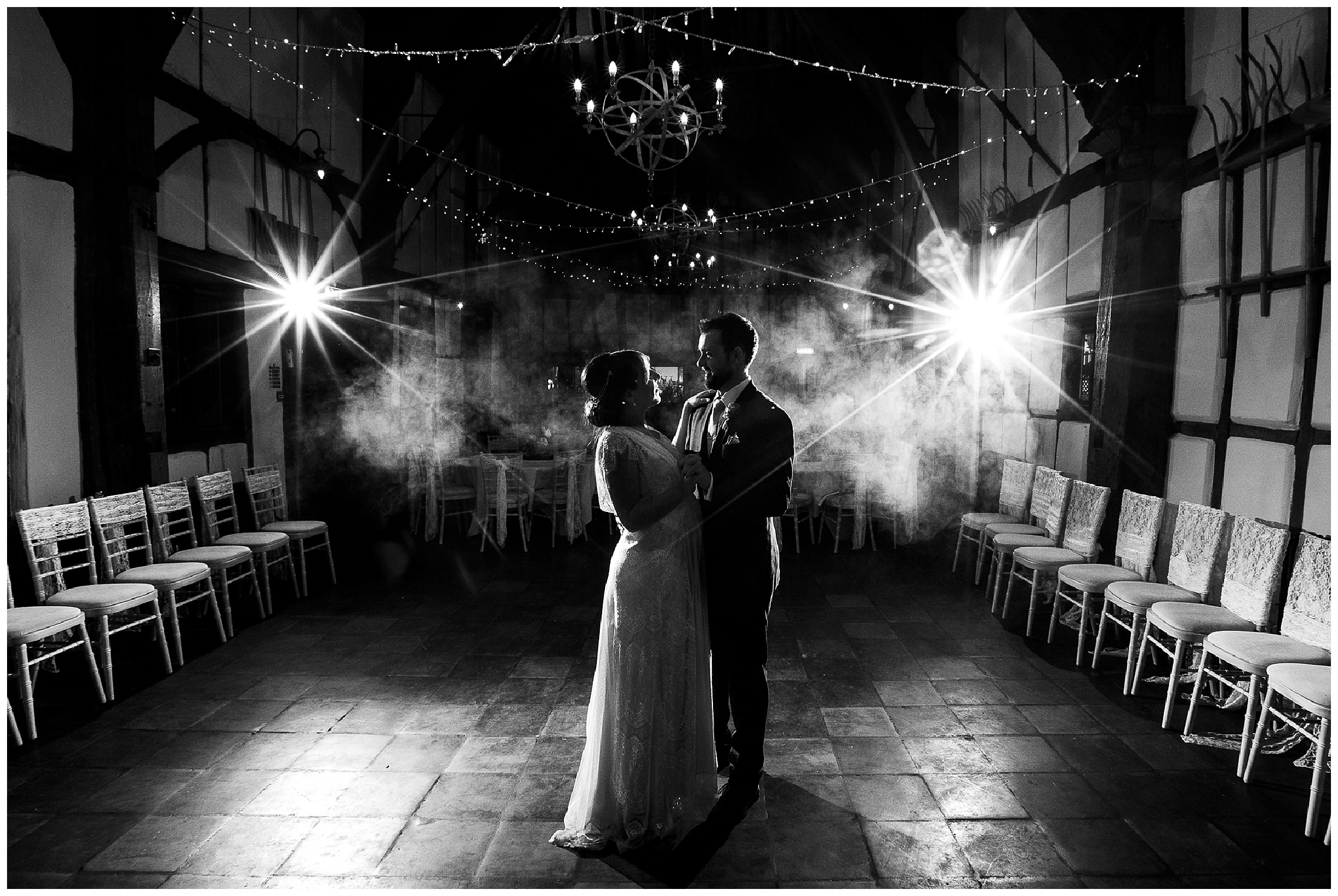 black and white image of bride and groom in spotlight with misty background