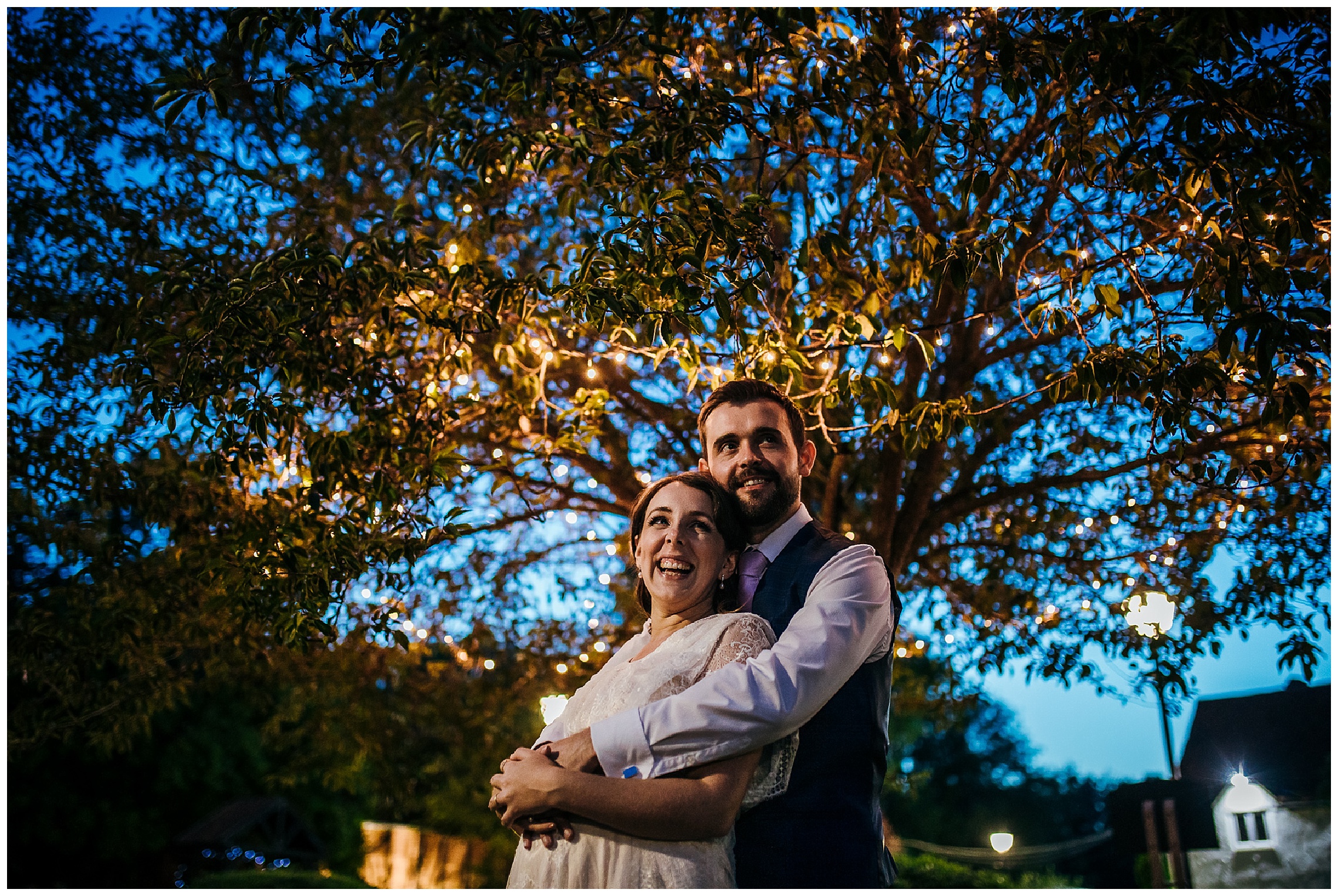 bride and groom under fairy light tree in the dark