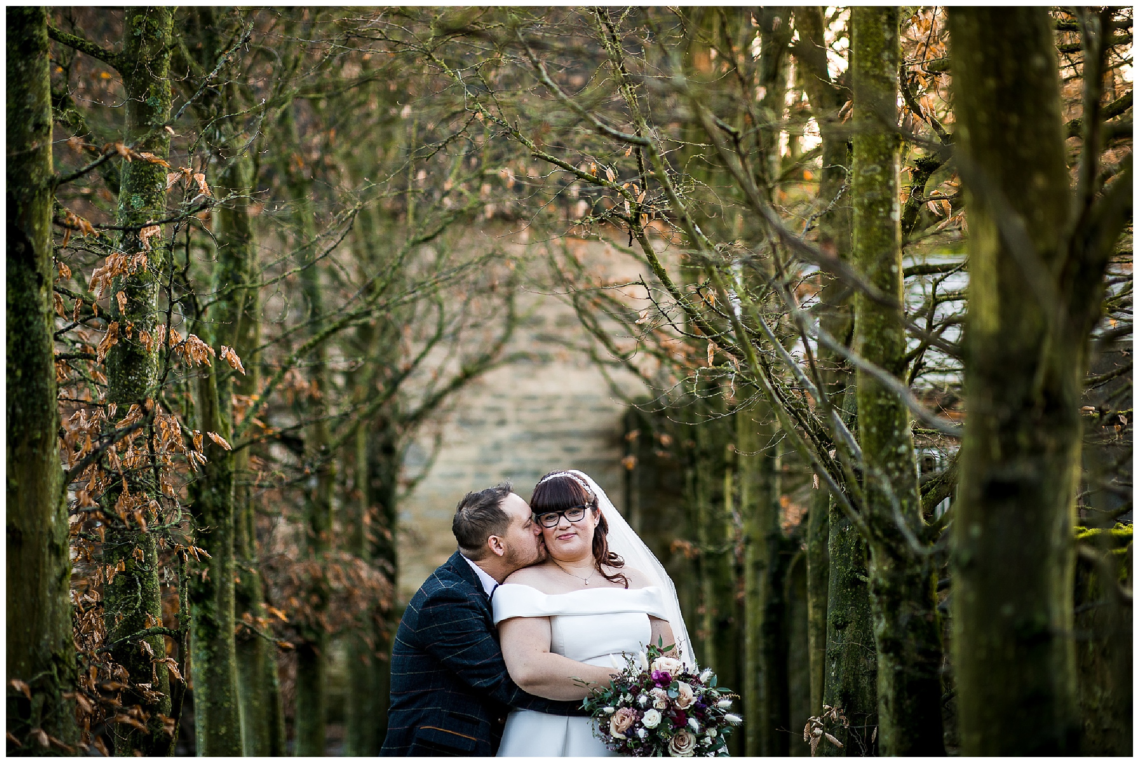 groom kisses bride on cheek from behind