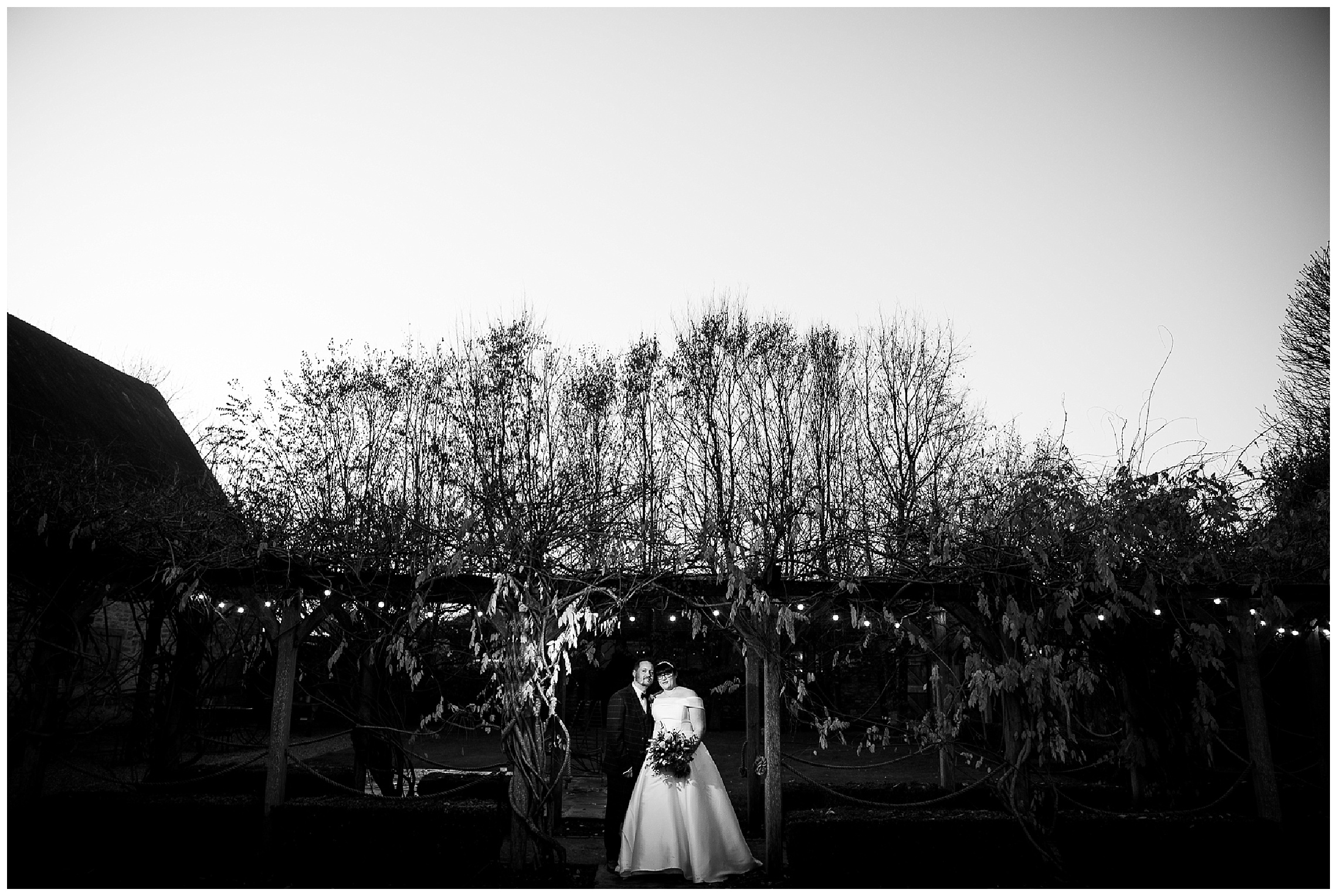 bride and groom in low light outside under canopy of plants