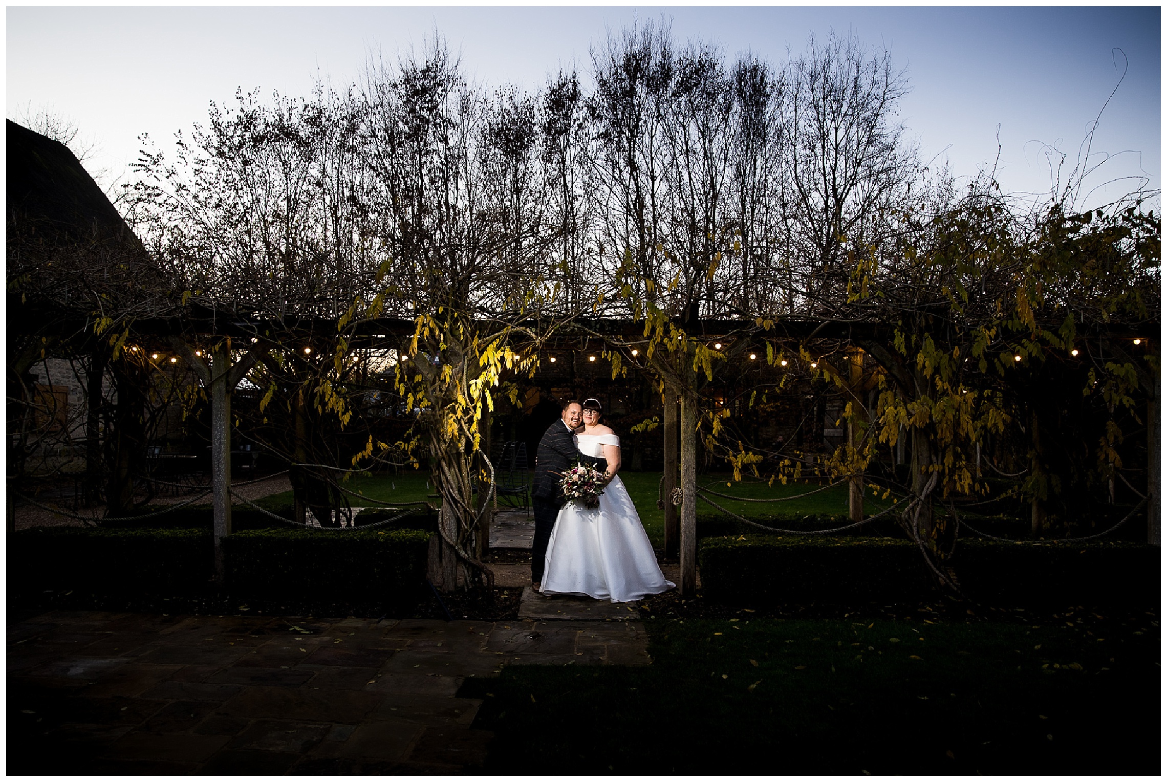 bride and groom outdoors as sun goes down in front of tythe barn in launton