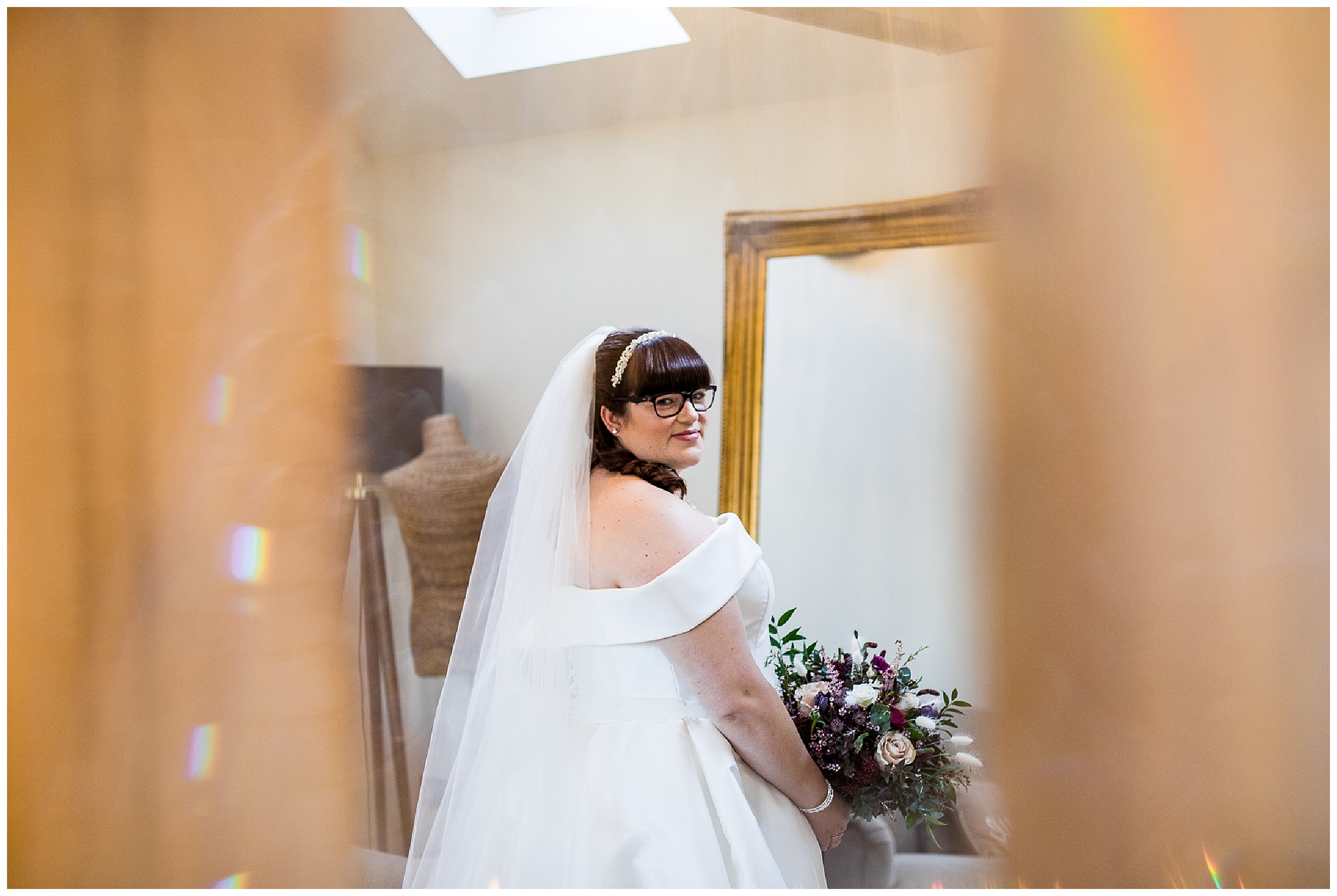 bride looking over shoulder in white bardot dress with big bouquet