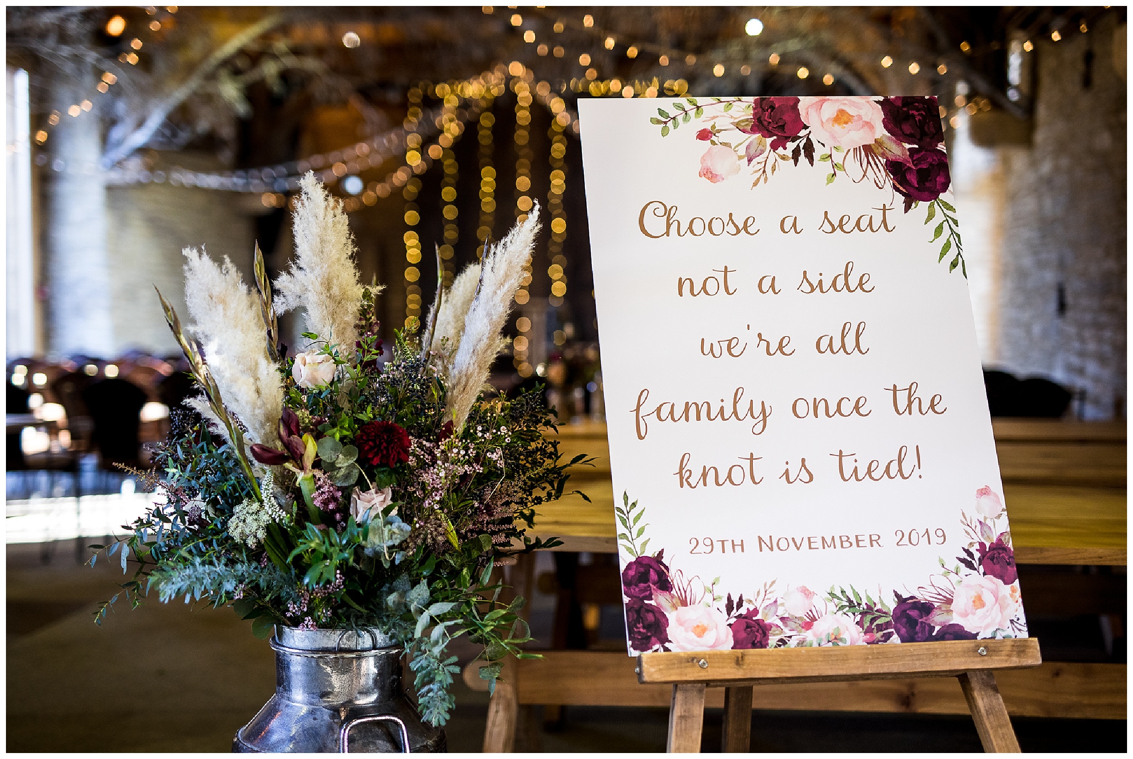 milk churn with pampas grass and rich florals in fairy light barn