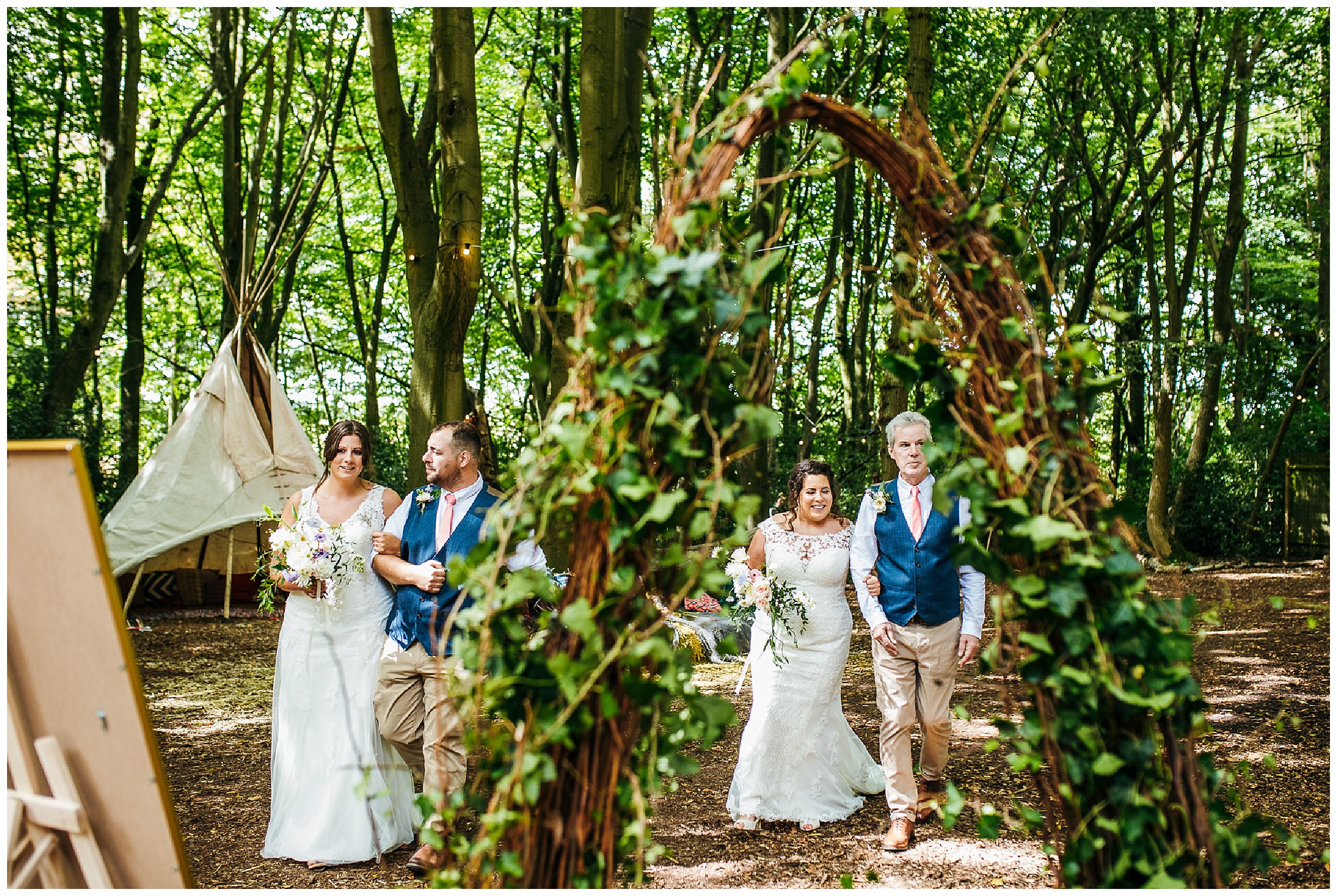 two lesbian brides walking down aisle together with their dad and brother at lilas wood