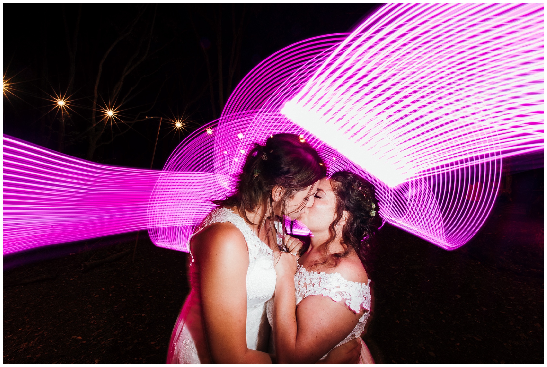 brides kiss in front of bright pink light