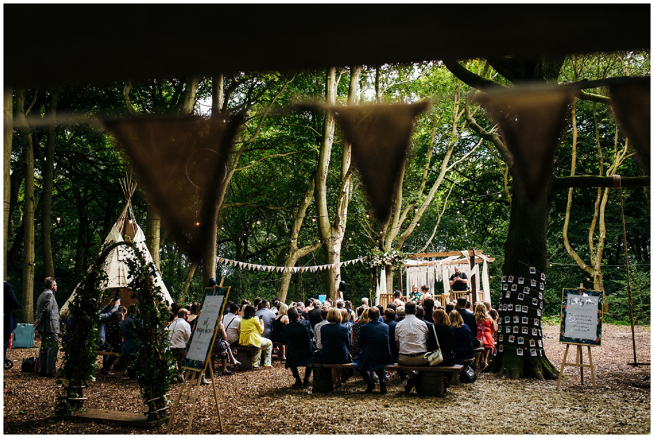 wedding ceremony taking place in woods with bunting
