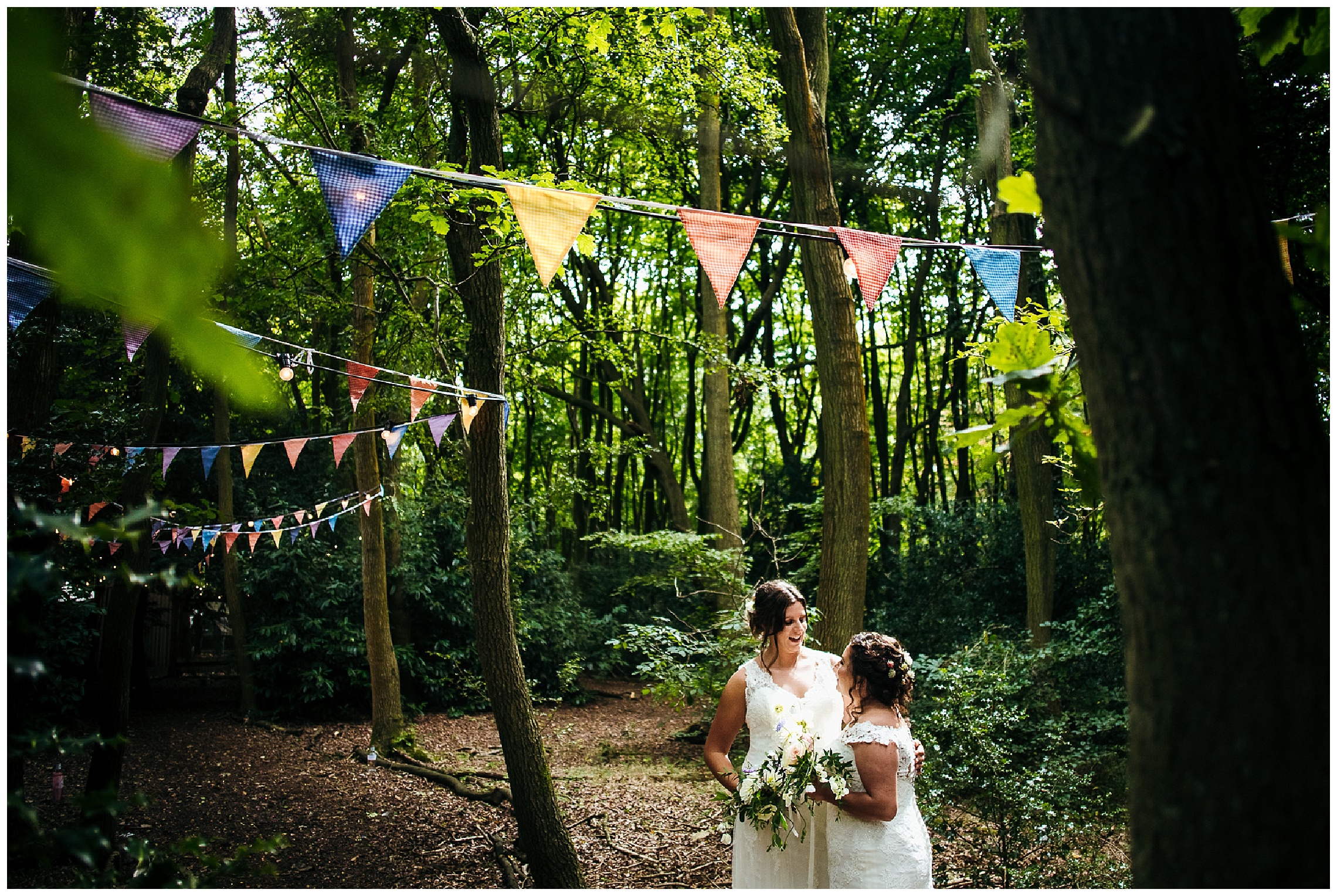 brides stand together and smile under bunting