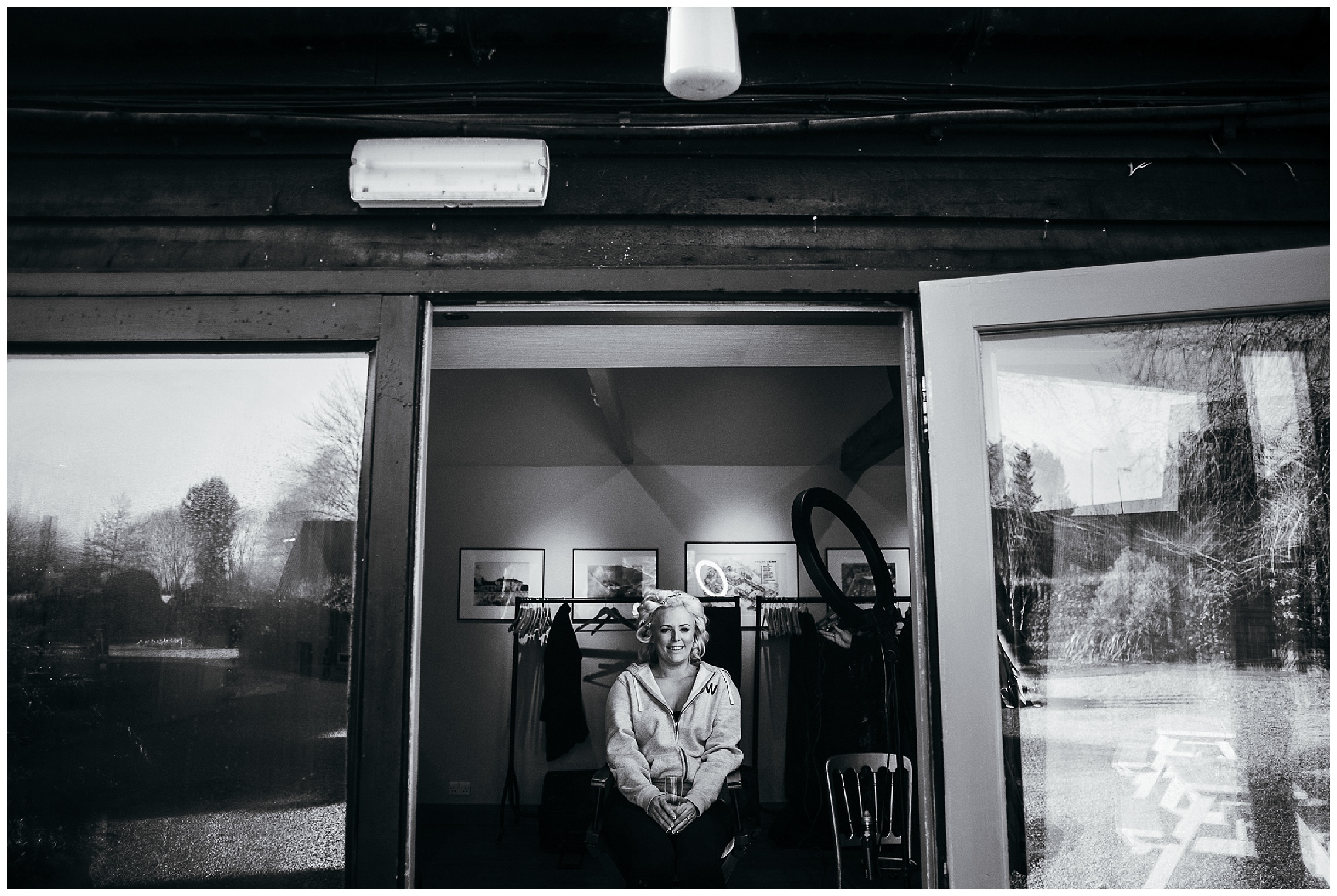 black and white image of bride with hair in rollers and make up being completed