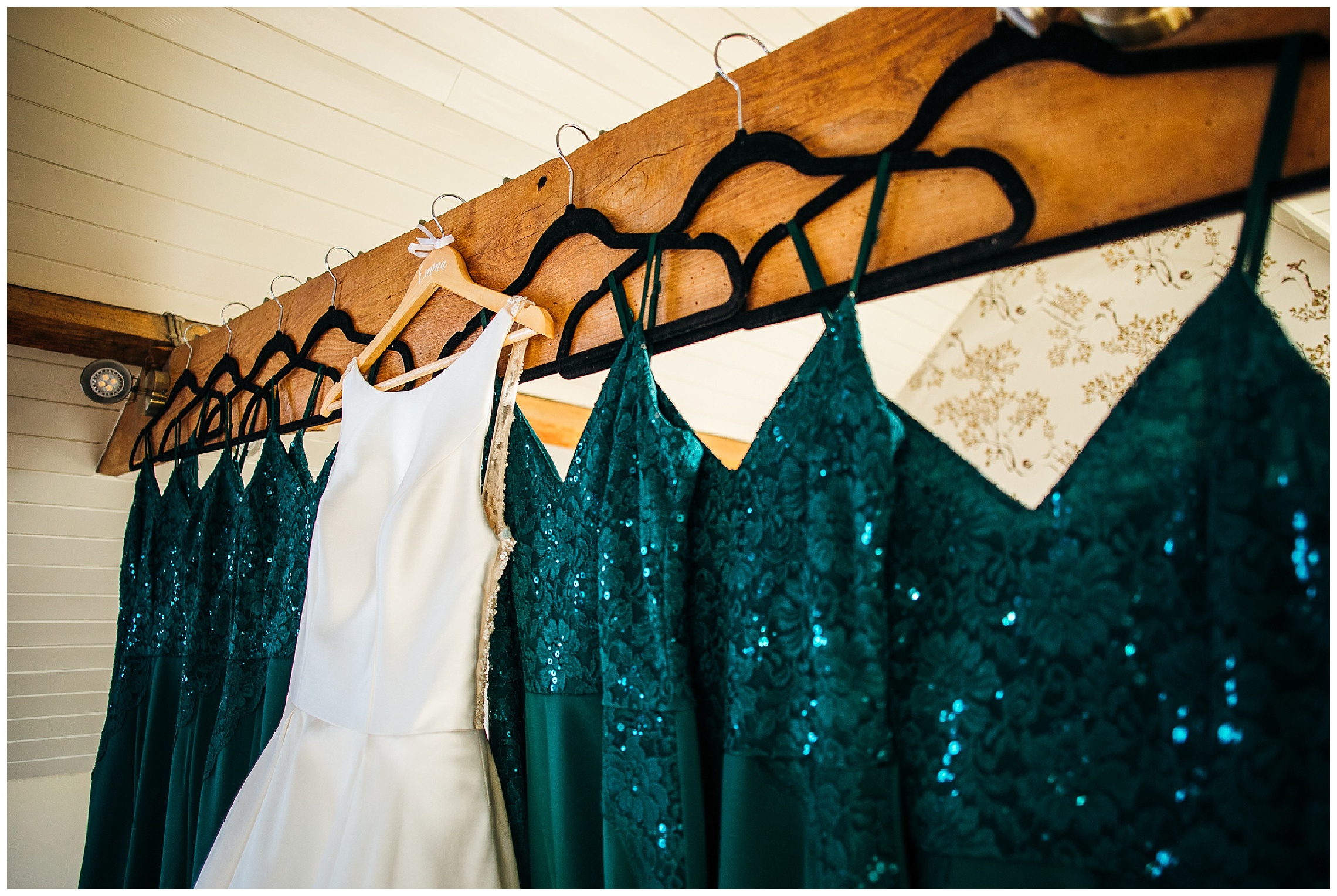 green sparkly bridesmaid dresses and white wedding dress hanging from beam