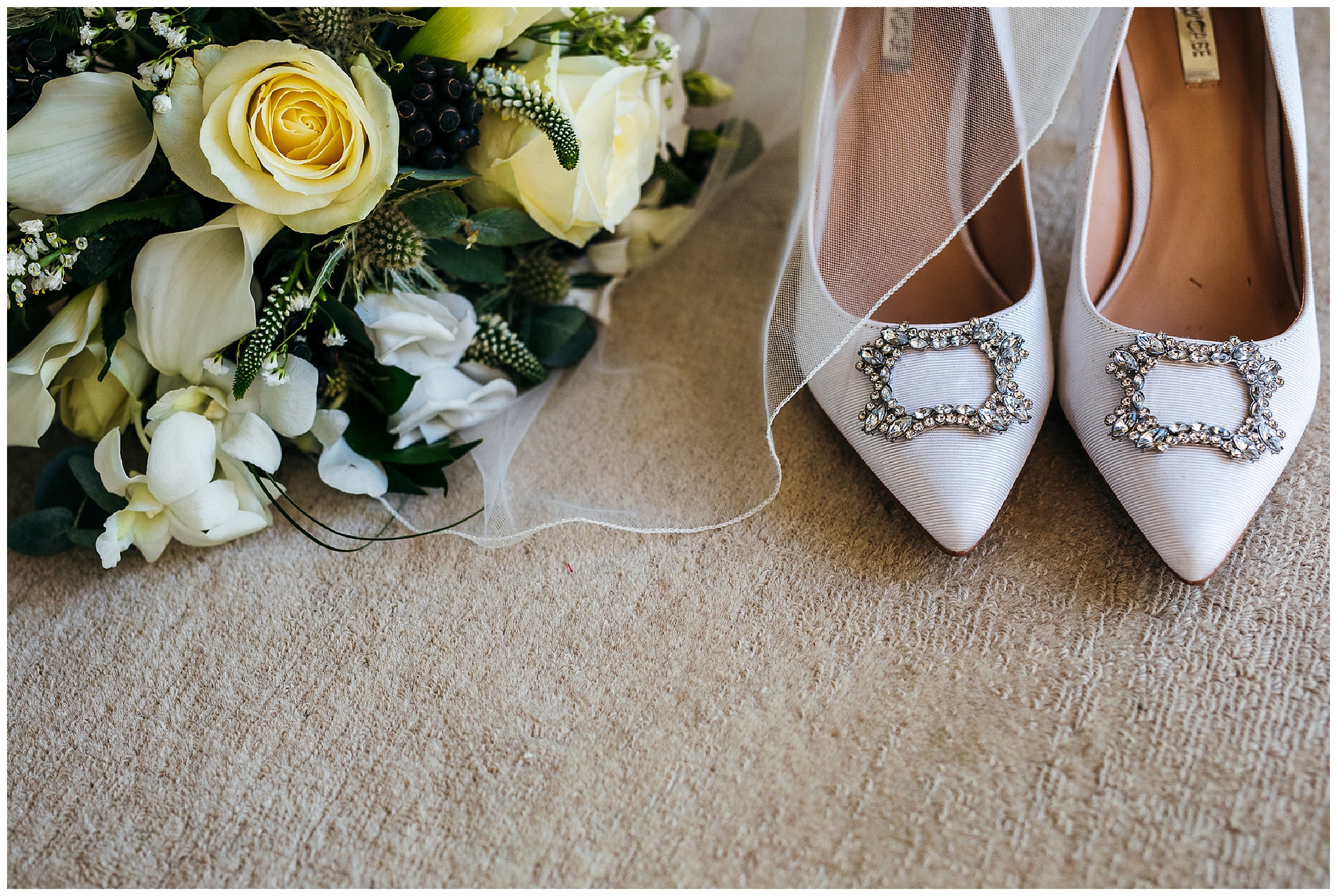 white wedding shoes with thin veil over them and white roses