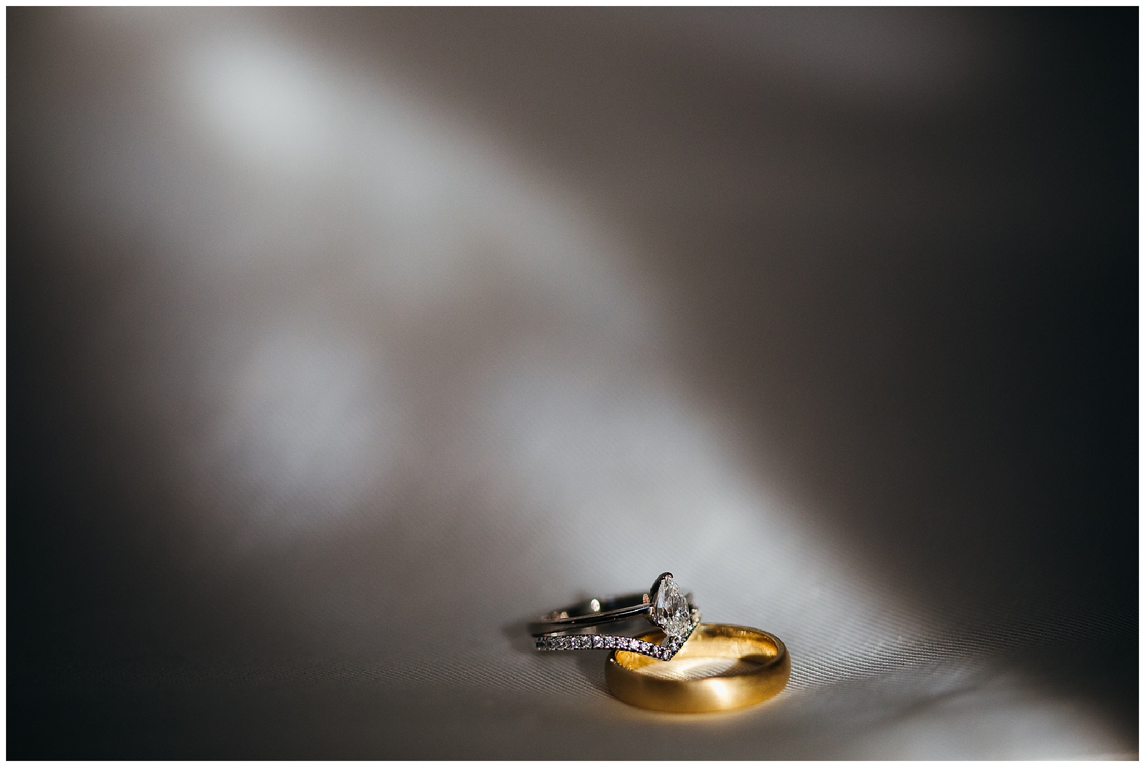 wedding rings in plume of light on white dress