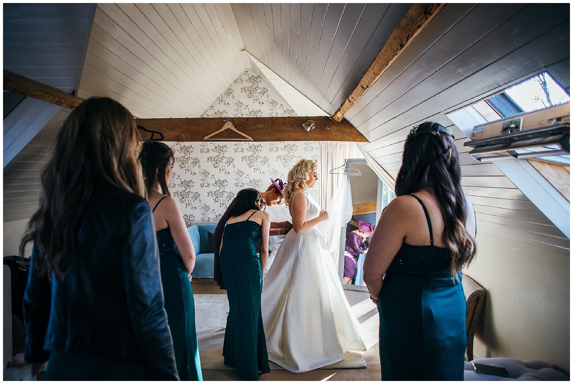 bride standing still as bridesmaids do her dress up and look onwards