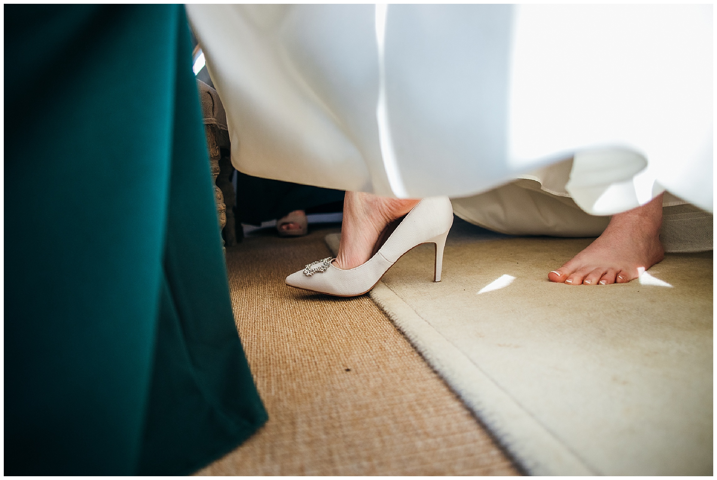 bride stepping into white wedding shoes