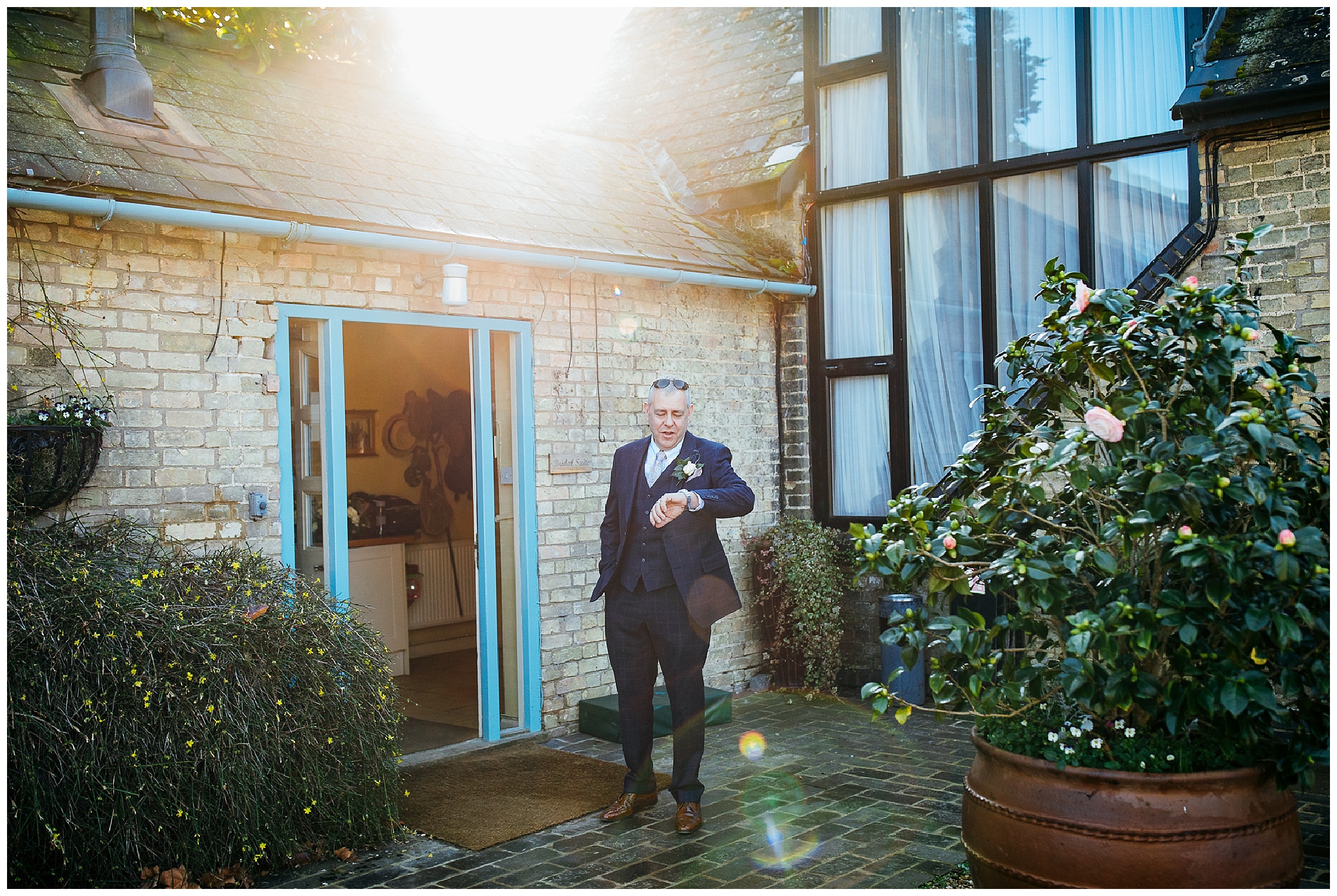 father of the bride standing outside waiting for bride and looking at watch