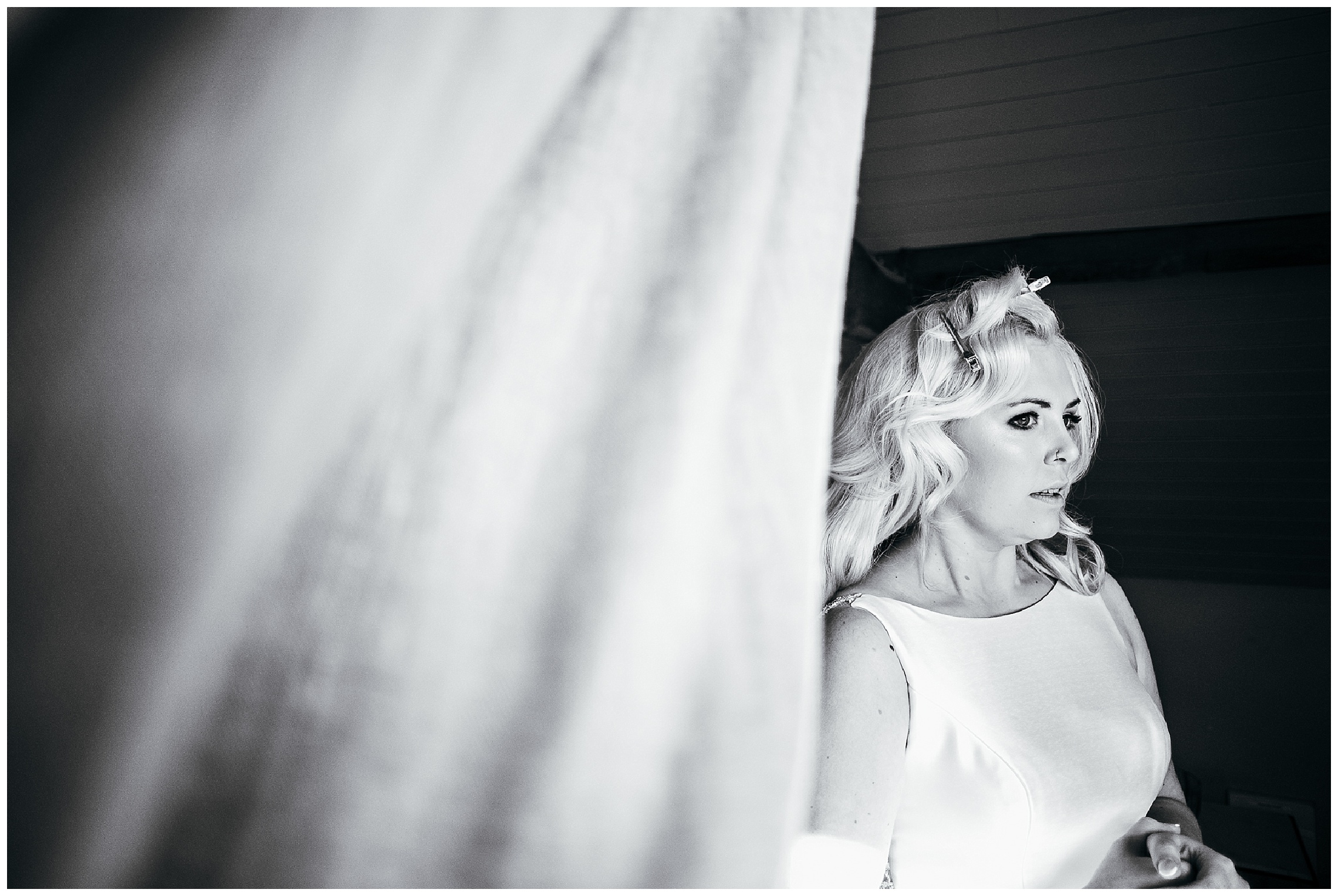 black and white image of bride nervously looking out of window