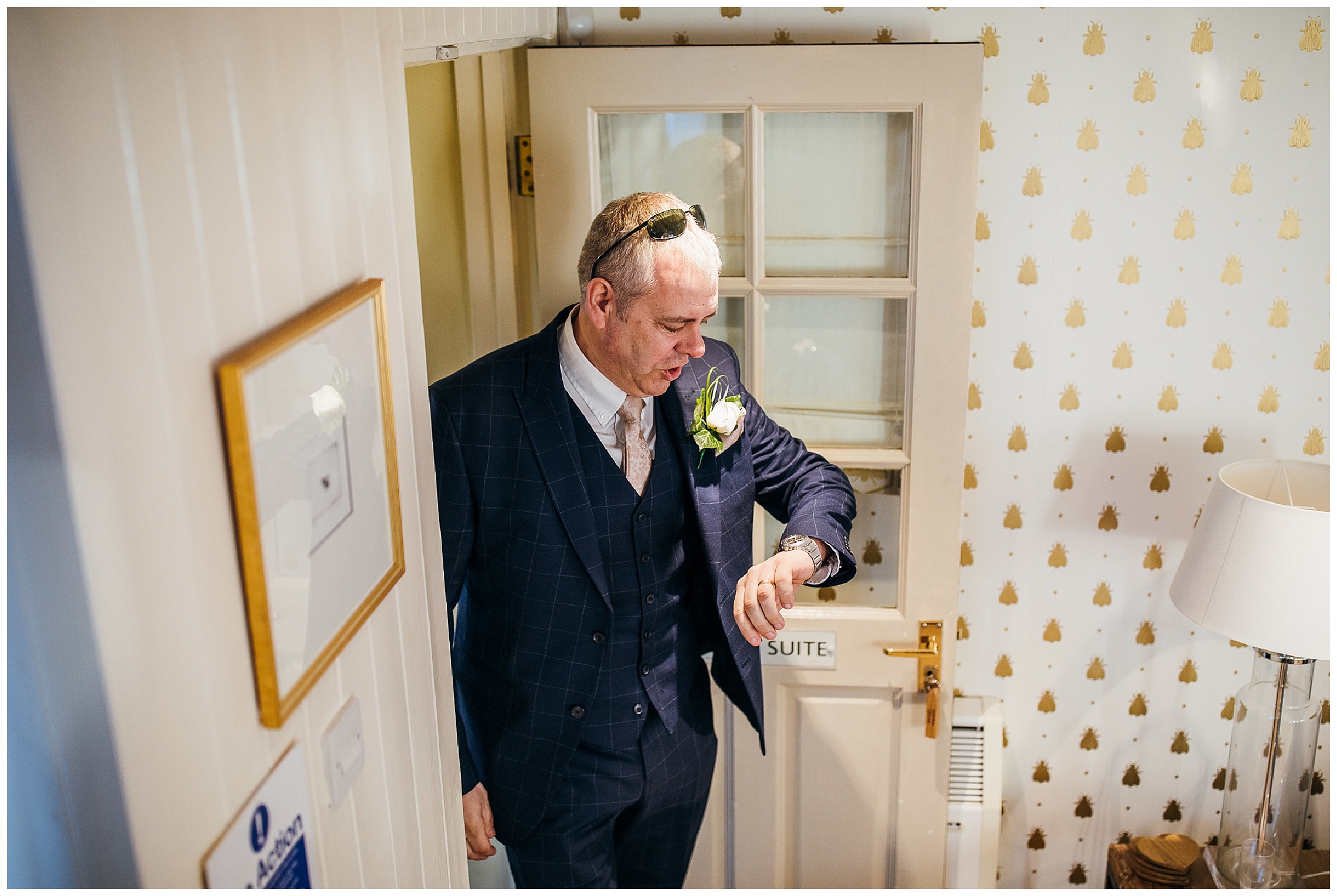 father of the bride standing at the bottom of stairs looking at watch