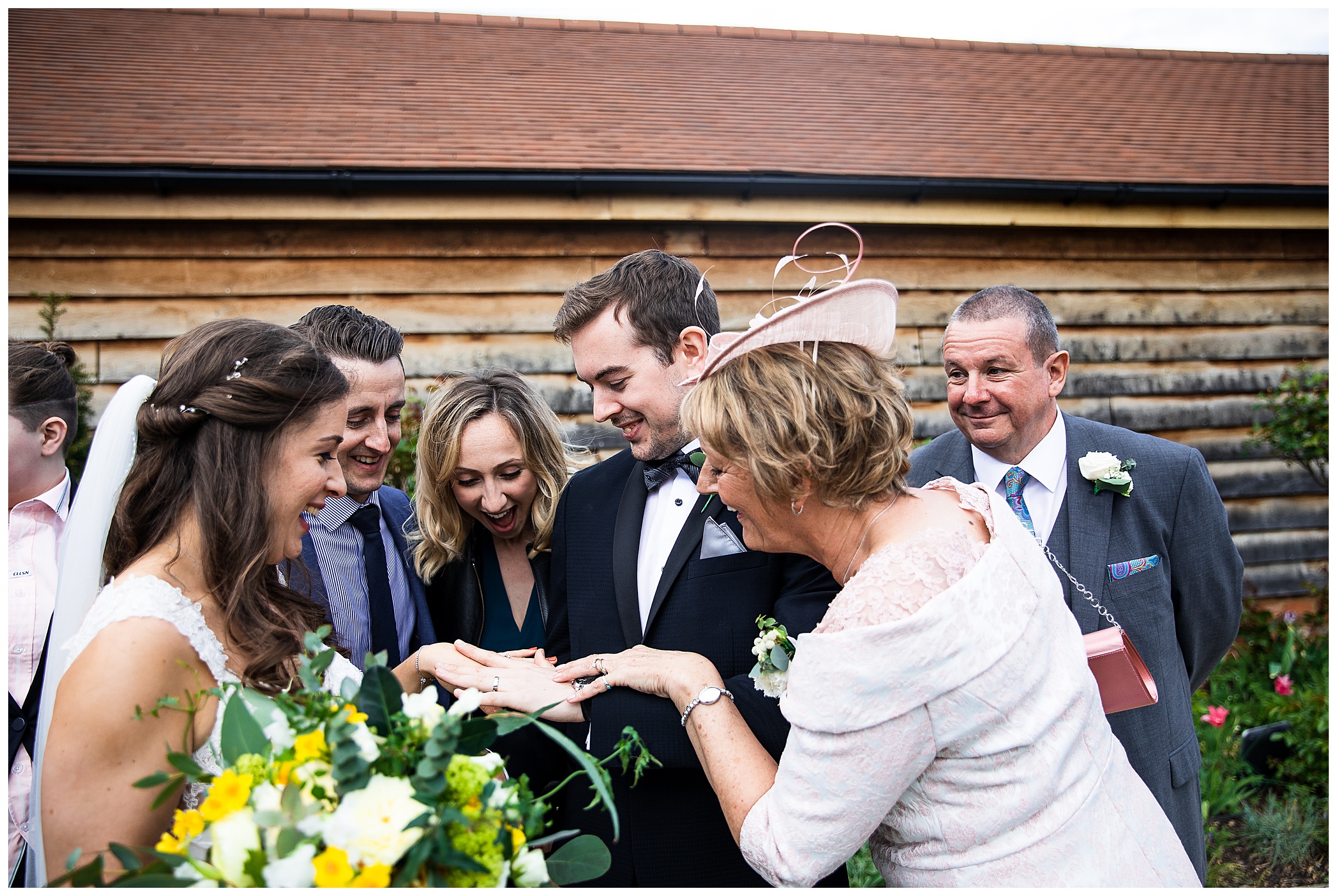 guests crowding round groom to look at wedding ring