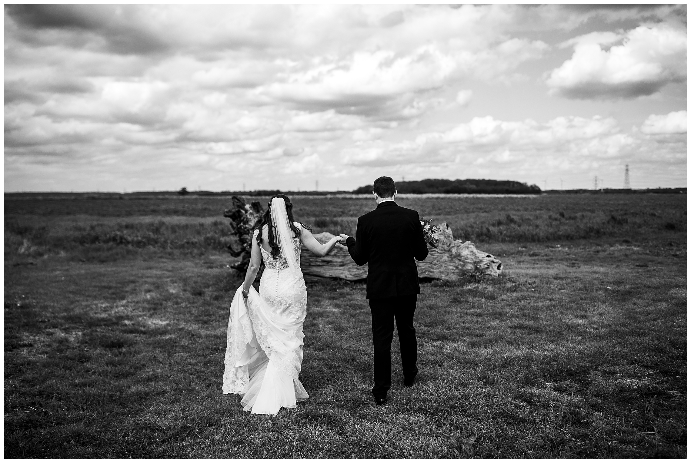 black and white image of bride and groom walking into sunset