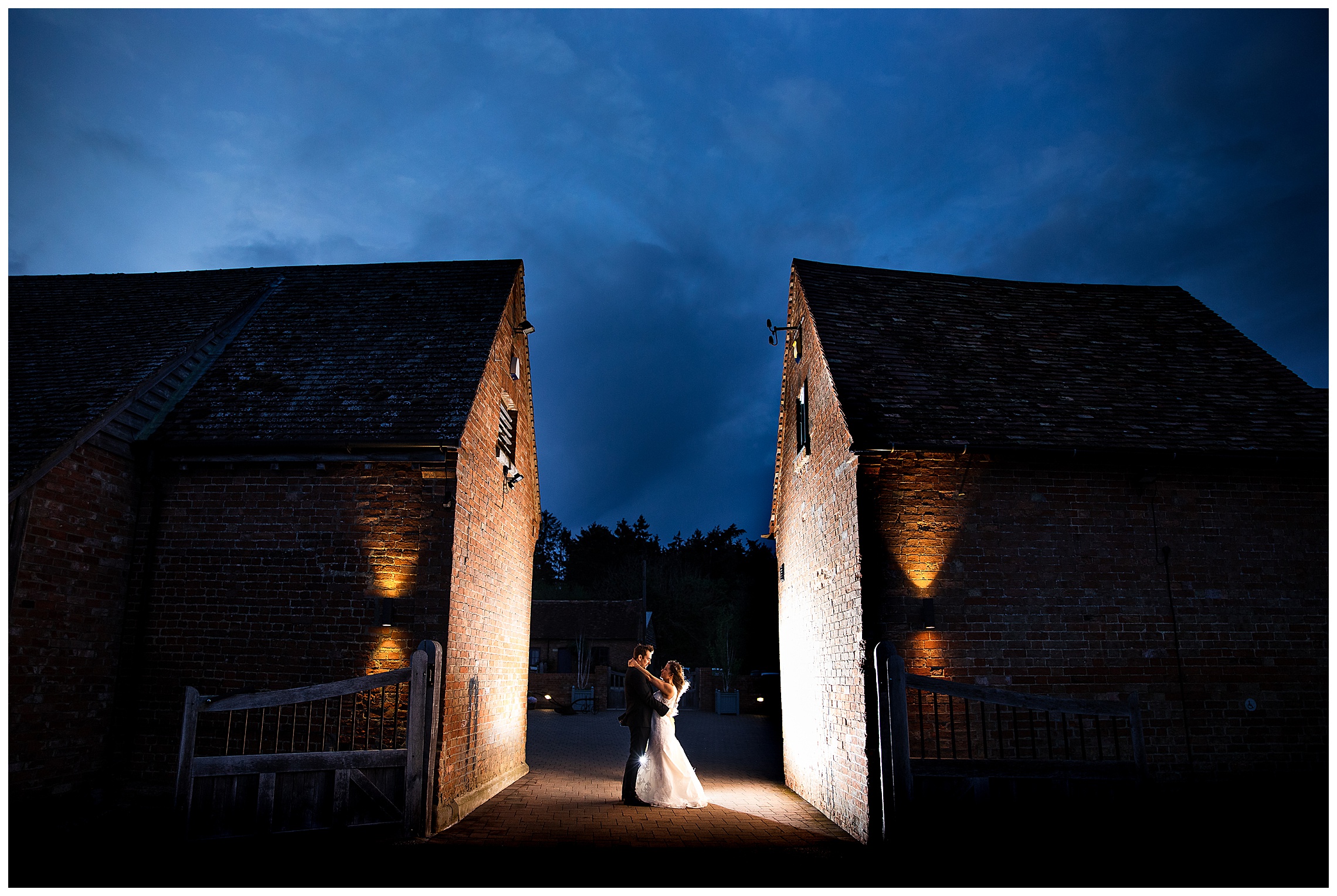 bride and groom backlit between buildings at bassmead manor barns