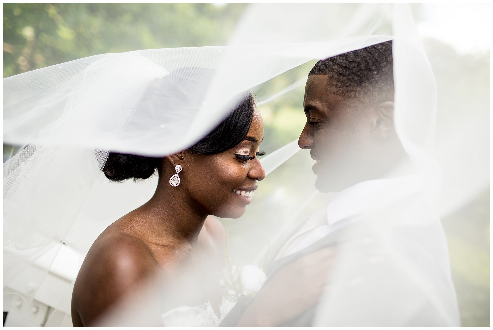 bride and groom kissing under white veil at stowe park