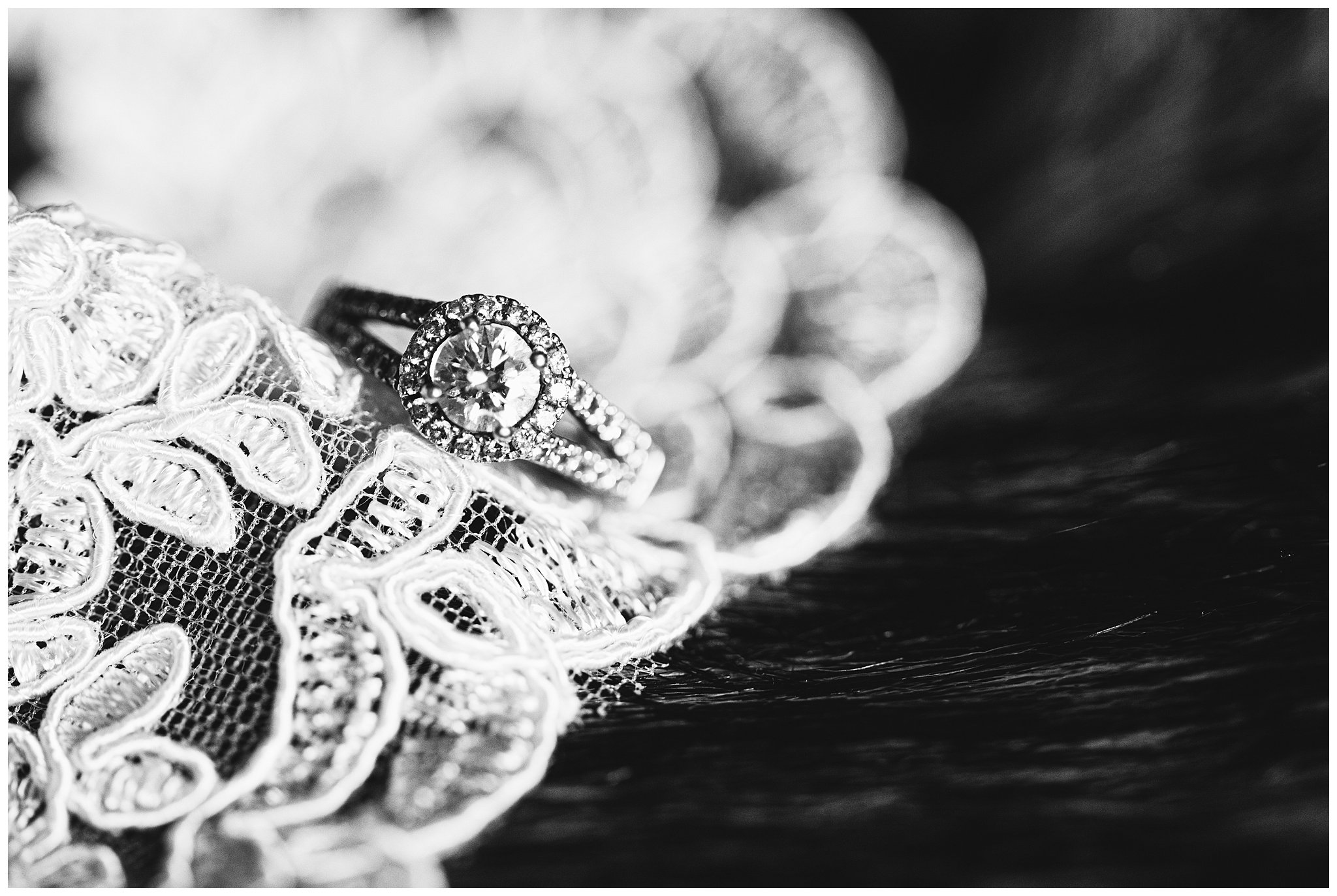 Large diamond engagement ring sat on lacy wedding dress