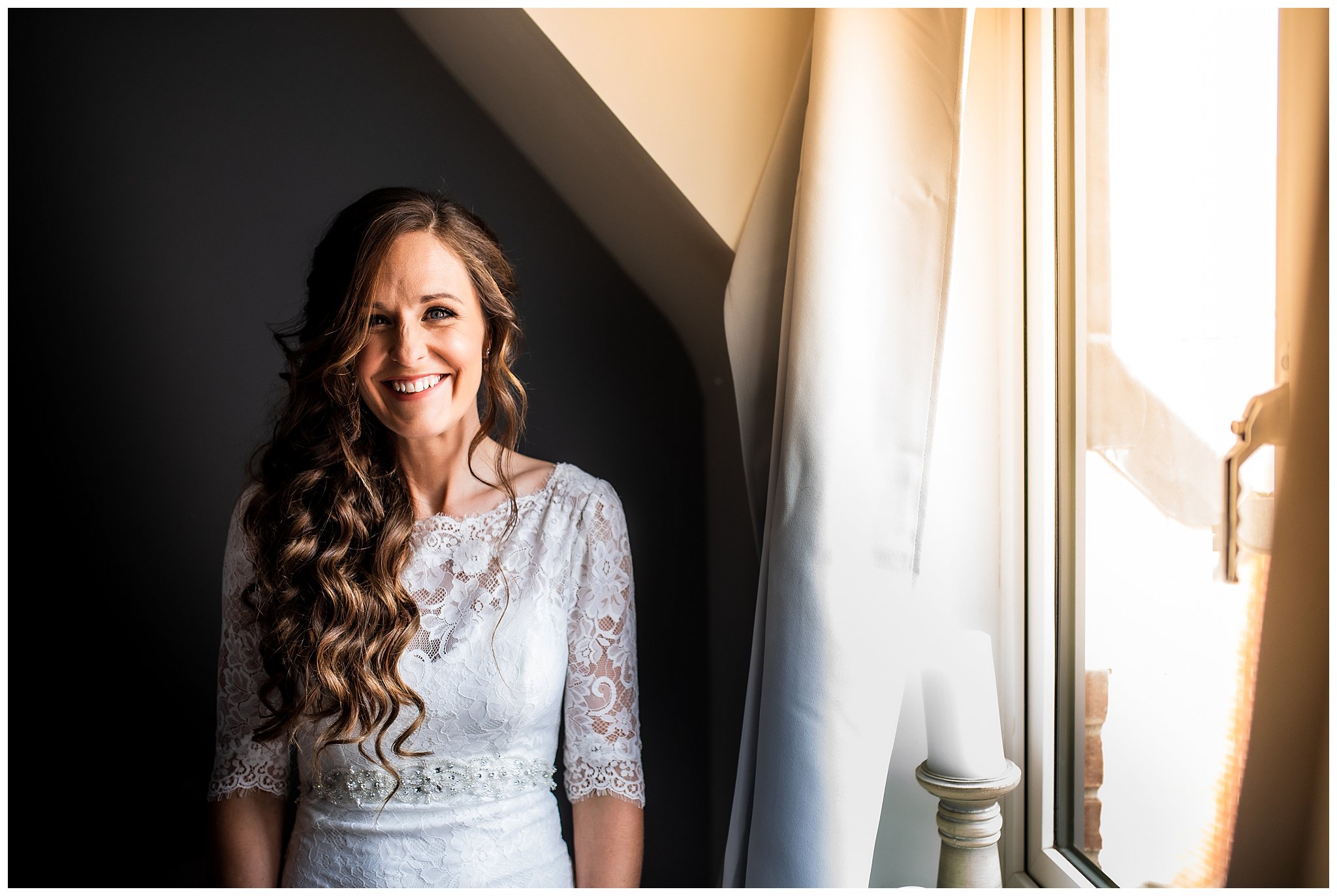 bride in lace wedding dress smiling by window