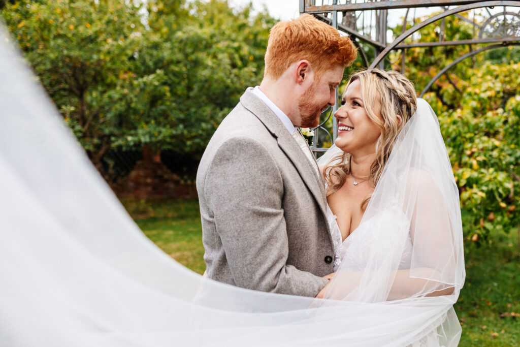 winters tale country barn wedding, bride and groom stand with veil draped across them