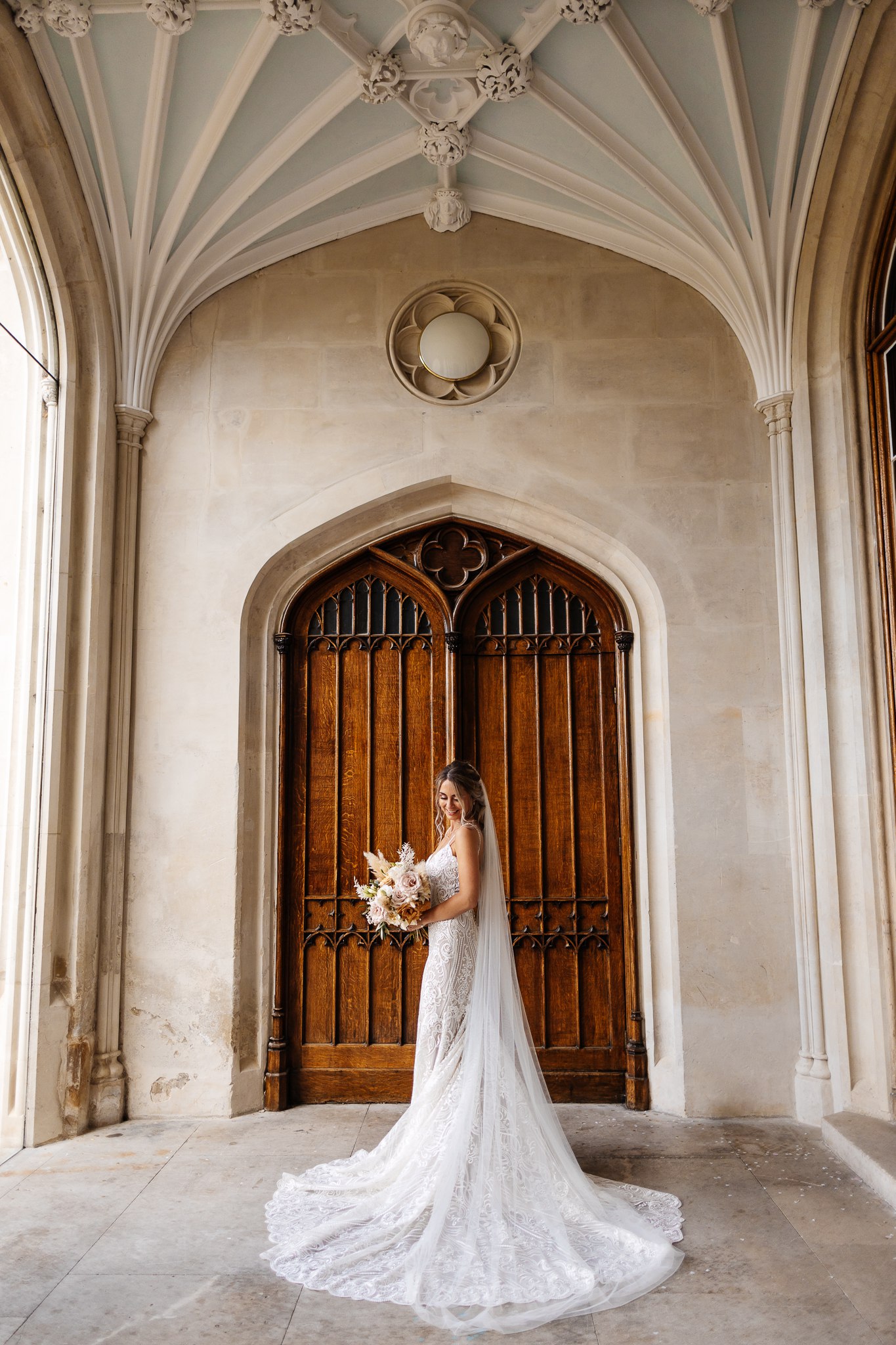 bride in long dress in front of doorway in the light at ashridge house 