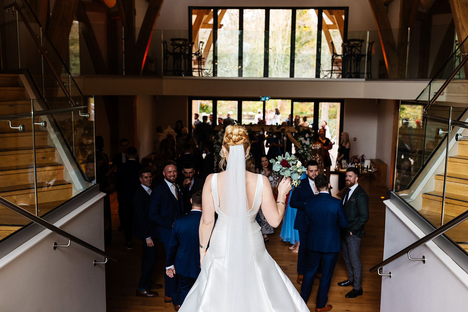 bride with high bun and veil walking down stairs at mill barns wedding venue 