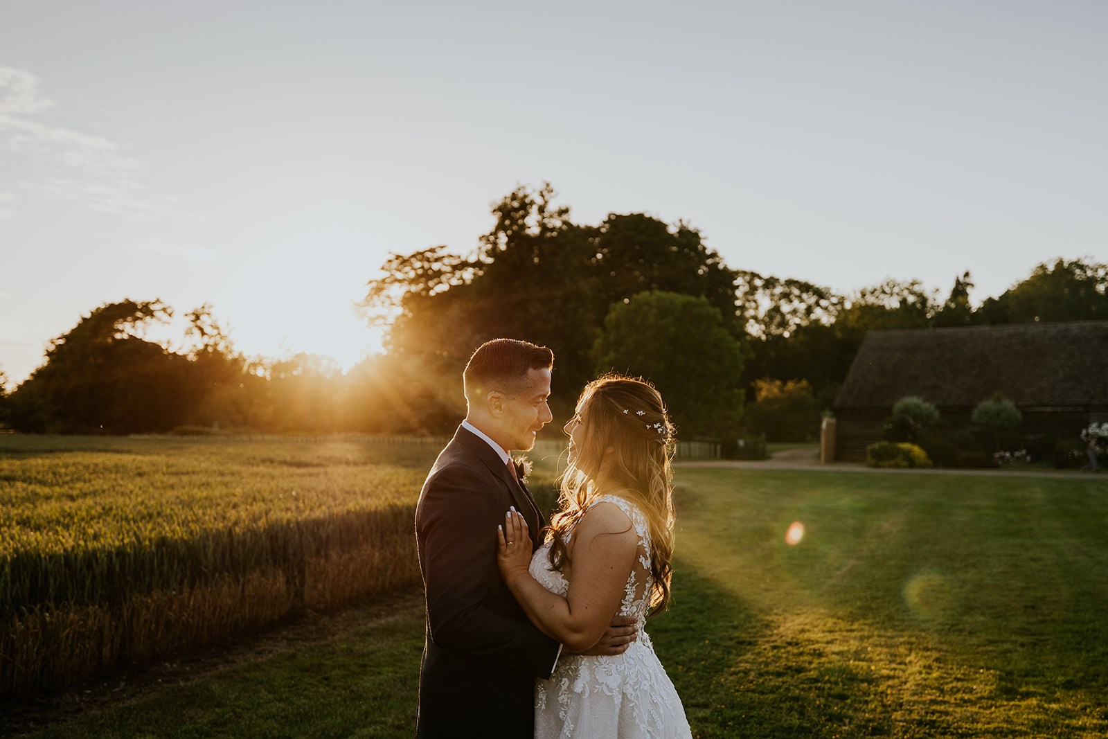 Couple watch the sun set over the fields by Bassmead