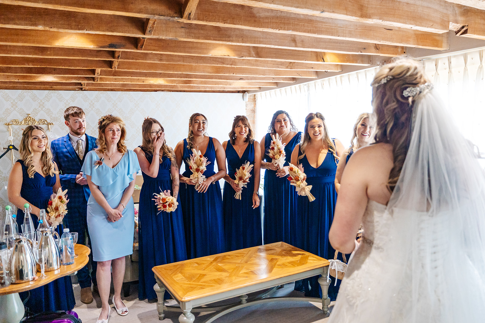 Bride's first look with bridal party, bridesmaids are in Navy dresses with dried flower bouquets 