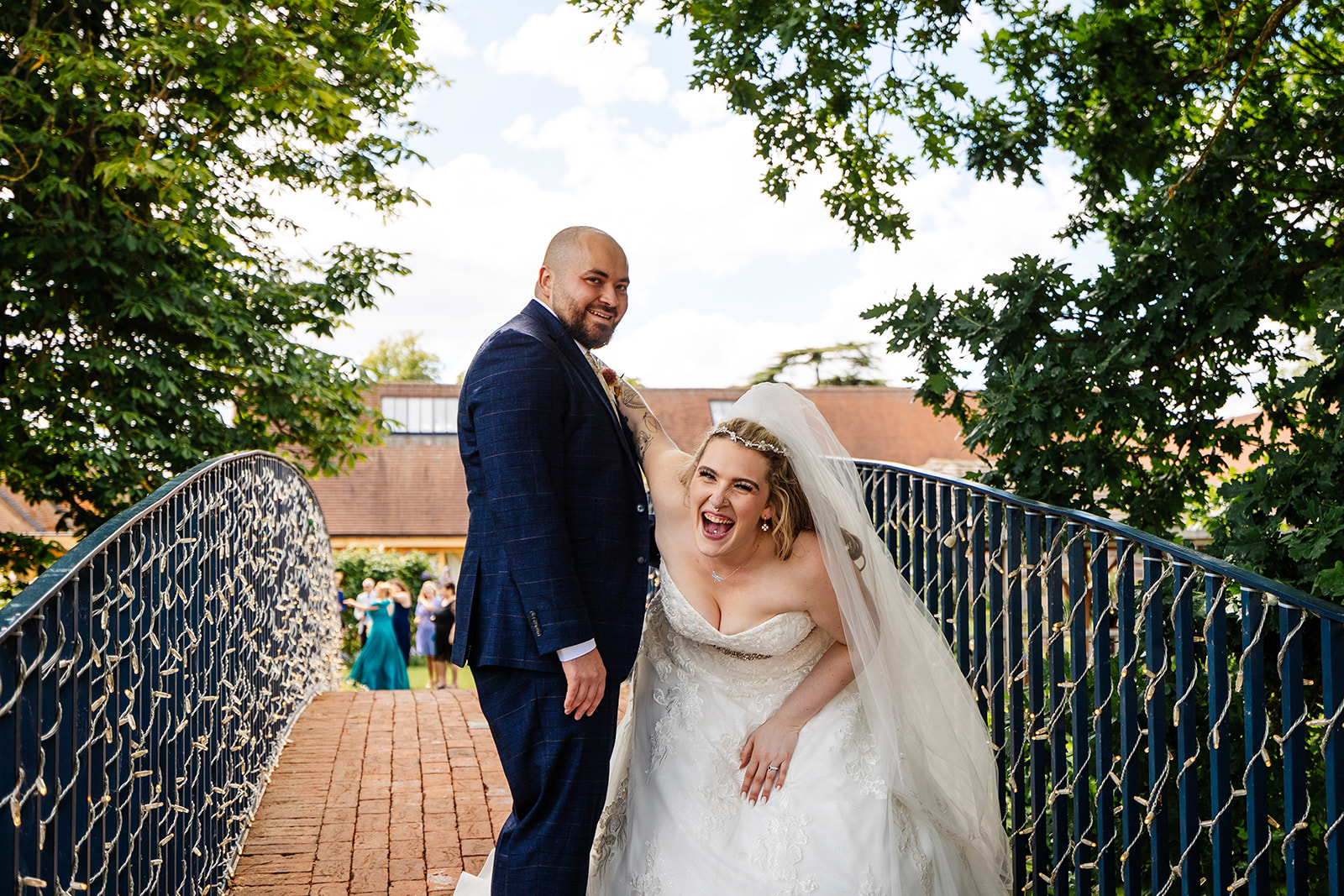 bassmead manor barns bride and groom stood laughing on the blue bridge