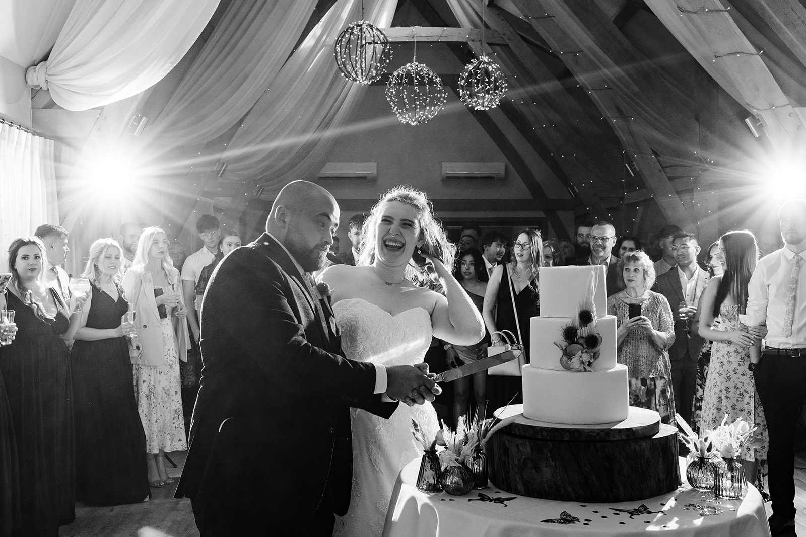 Couple cut cake, bride is looking at groom laughing 