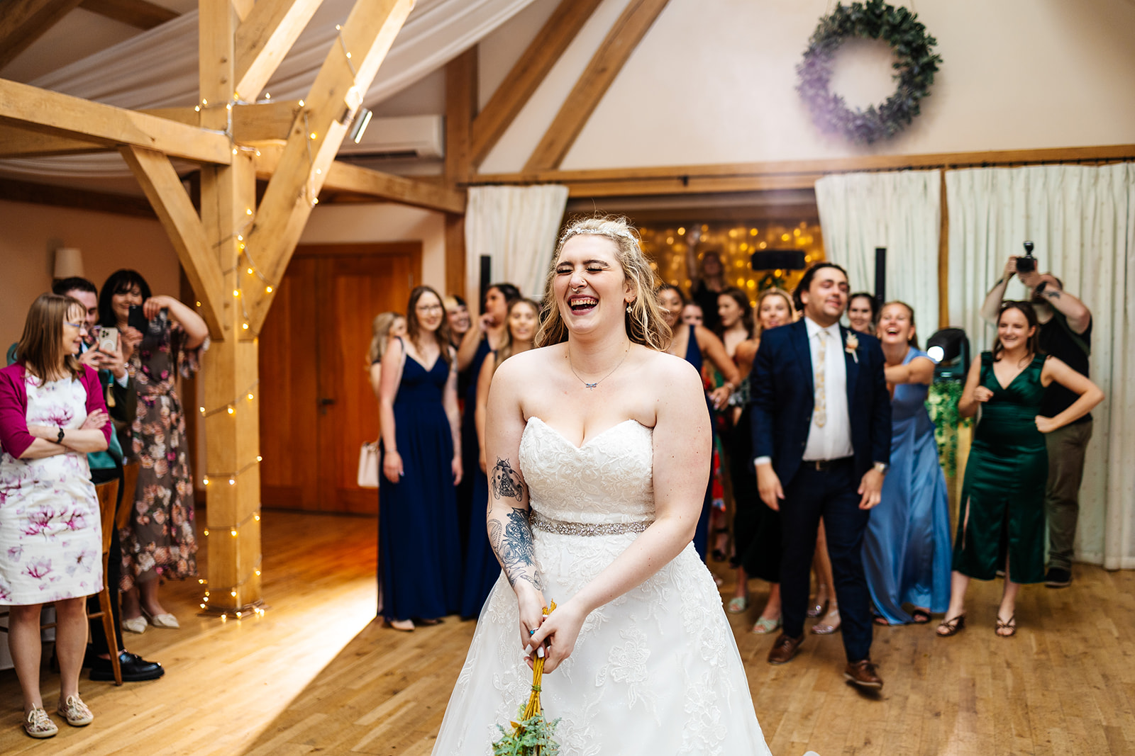 Bride readies herself to throw bouquet, some guests are ready behind to try and catch 