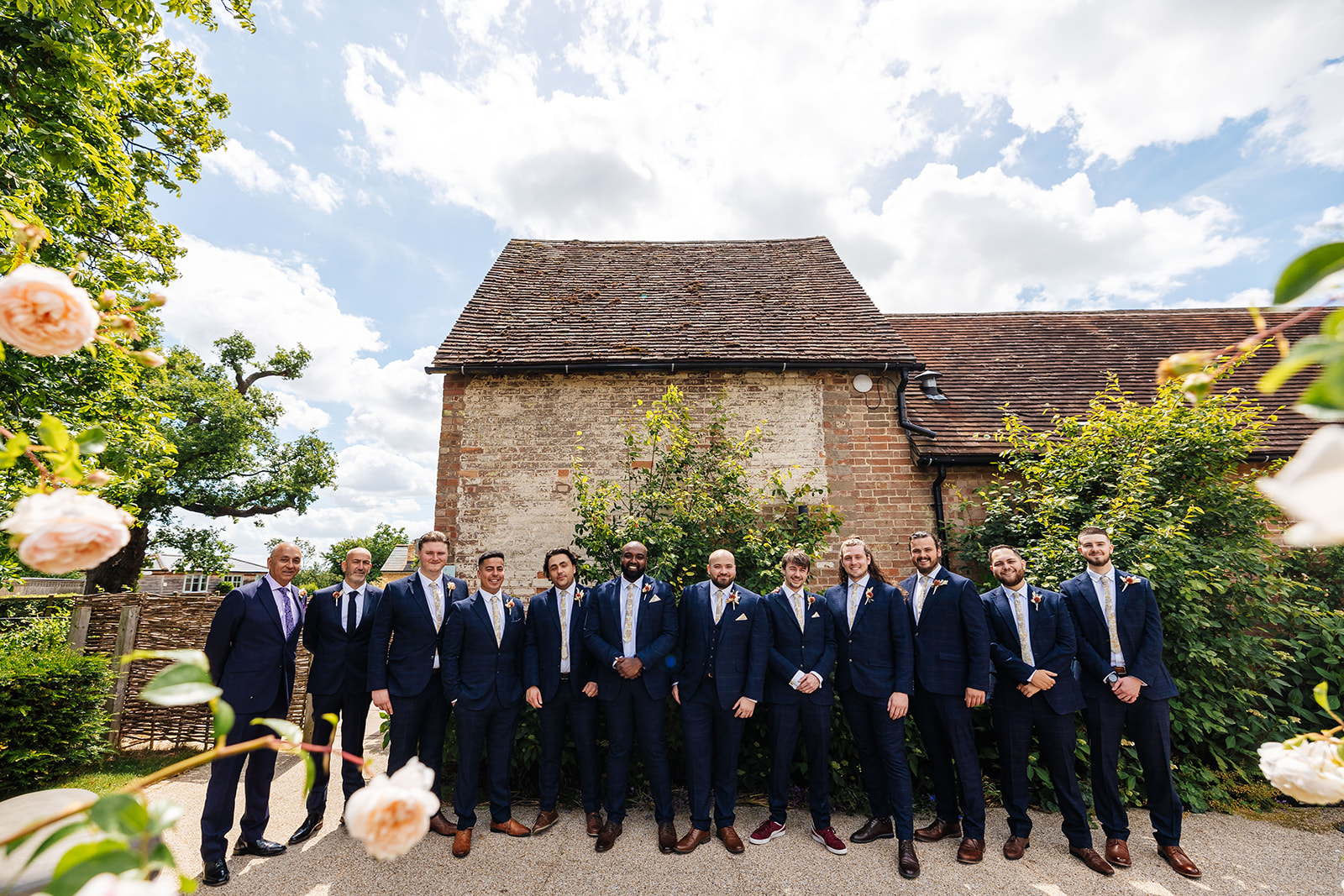 Groomsmen stood infront of Bassmead, in dark blue suits 