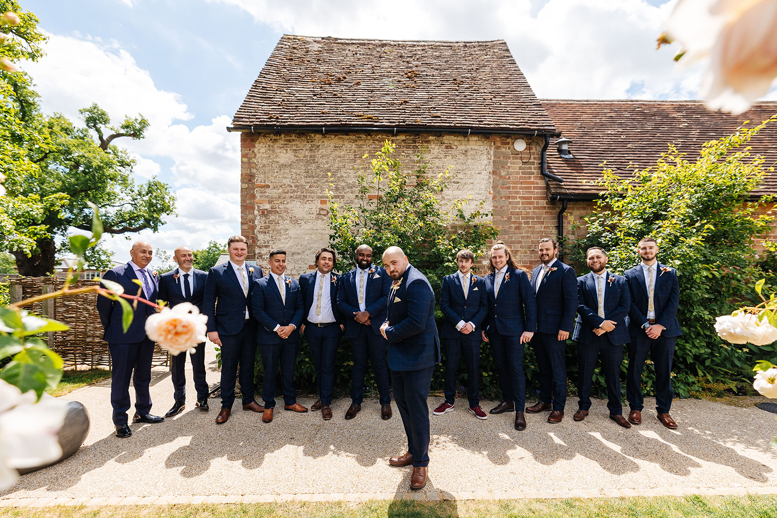 Groom takes centre stage with a pose infront of Bassmead, groomsmen behind 
