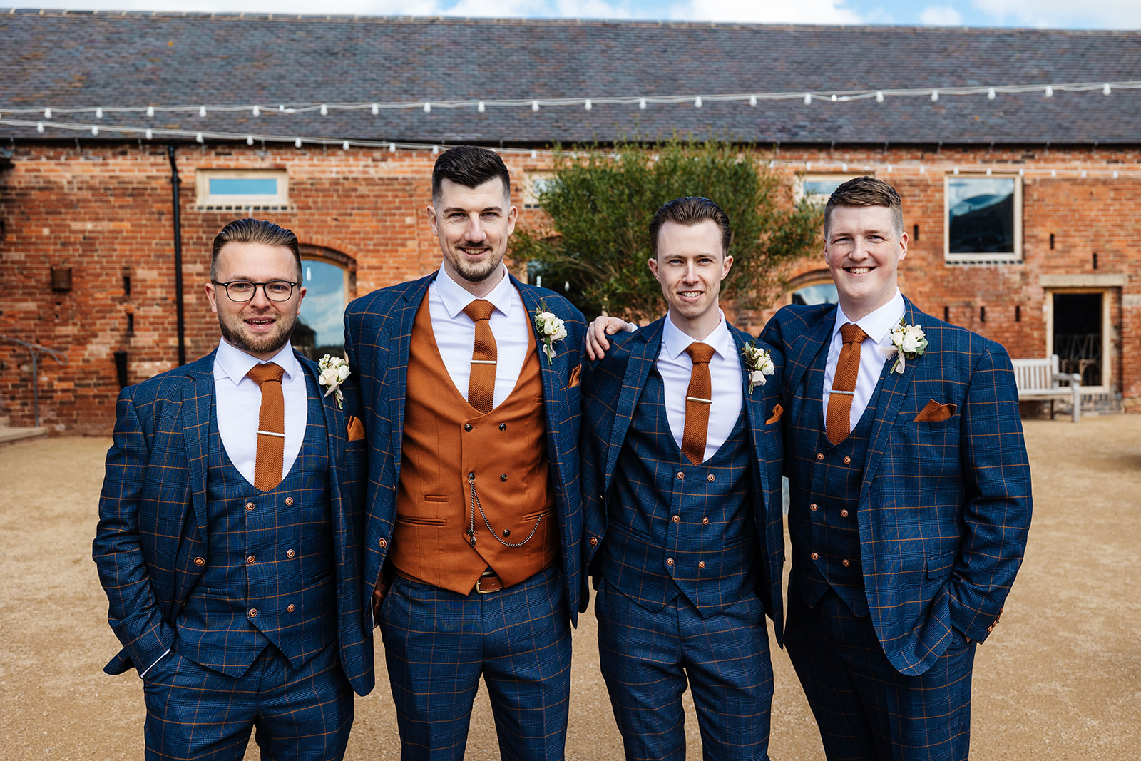 Groomsmen in blue and brown chequered suits outside venue 