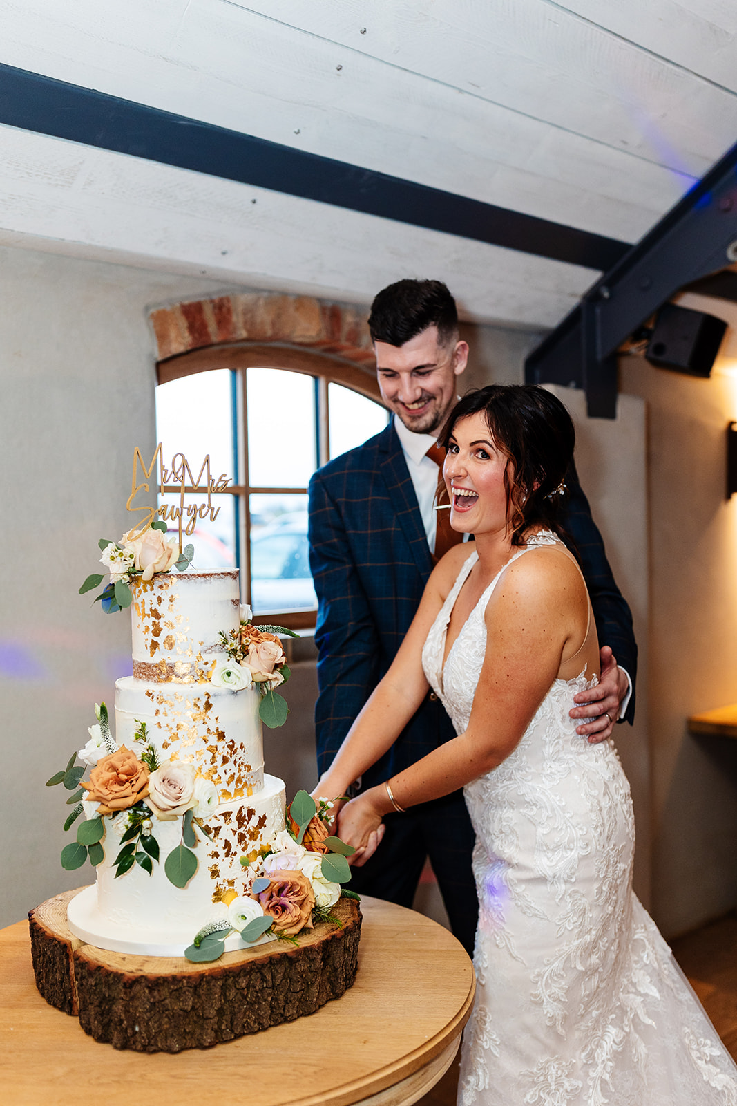 Bride and groom cutting the cake, both are laughing 