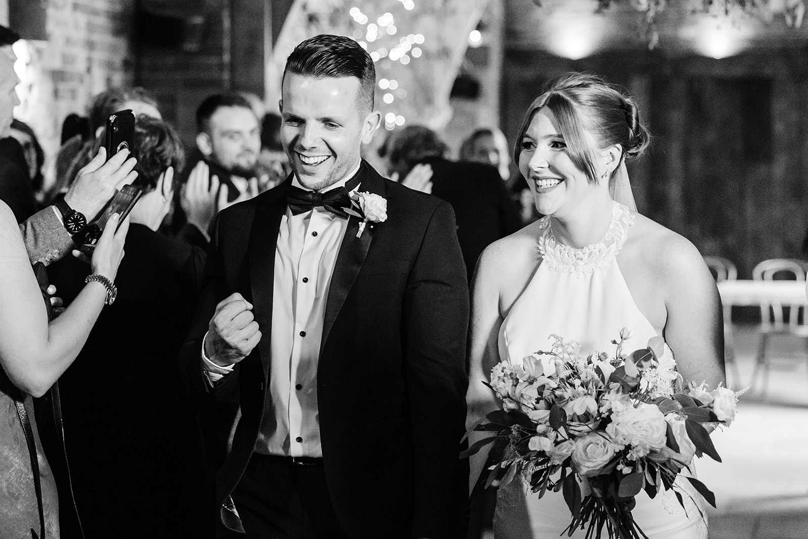 Couple exit ceremony holding hands in black and white 