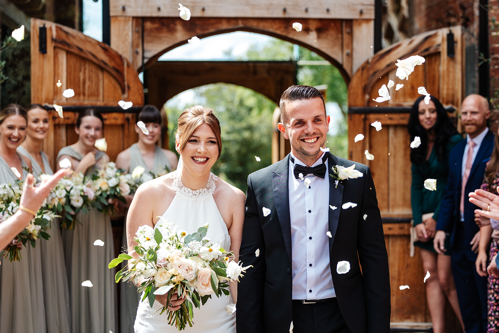 Couple walk through confetti thrown by guests 