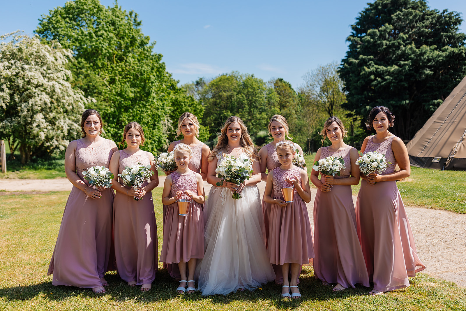 Bride and bridesmaids in pink dresses outside tipi before ceremony 